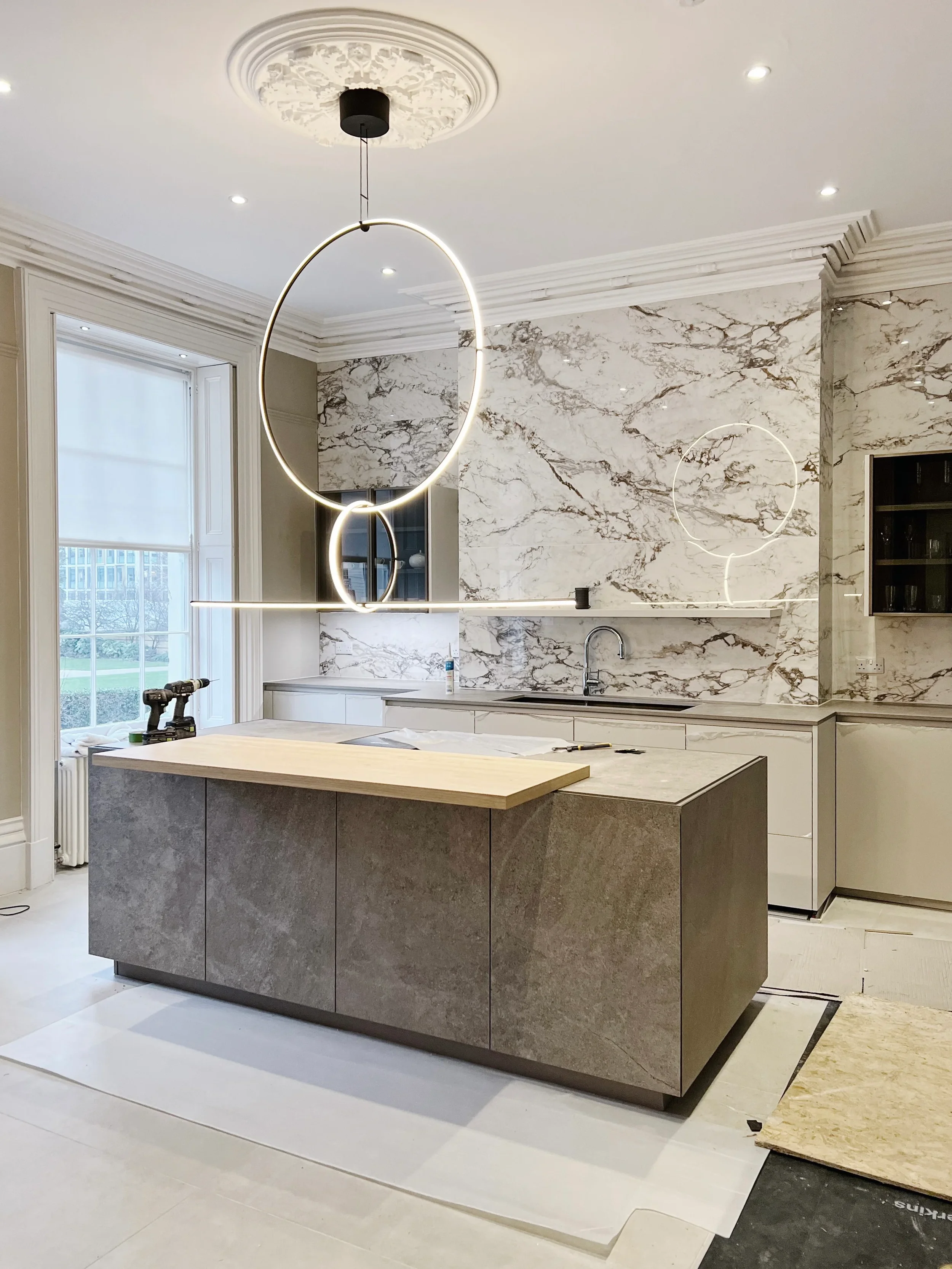Contemporary Zampieri kitchen inside a Regency house featuring a former chimney breast clad in Keope 6mm large format white marble-effect porcelain, paired with an Inalco stone-effect porcelain kitchen island and large format floor tiles.