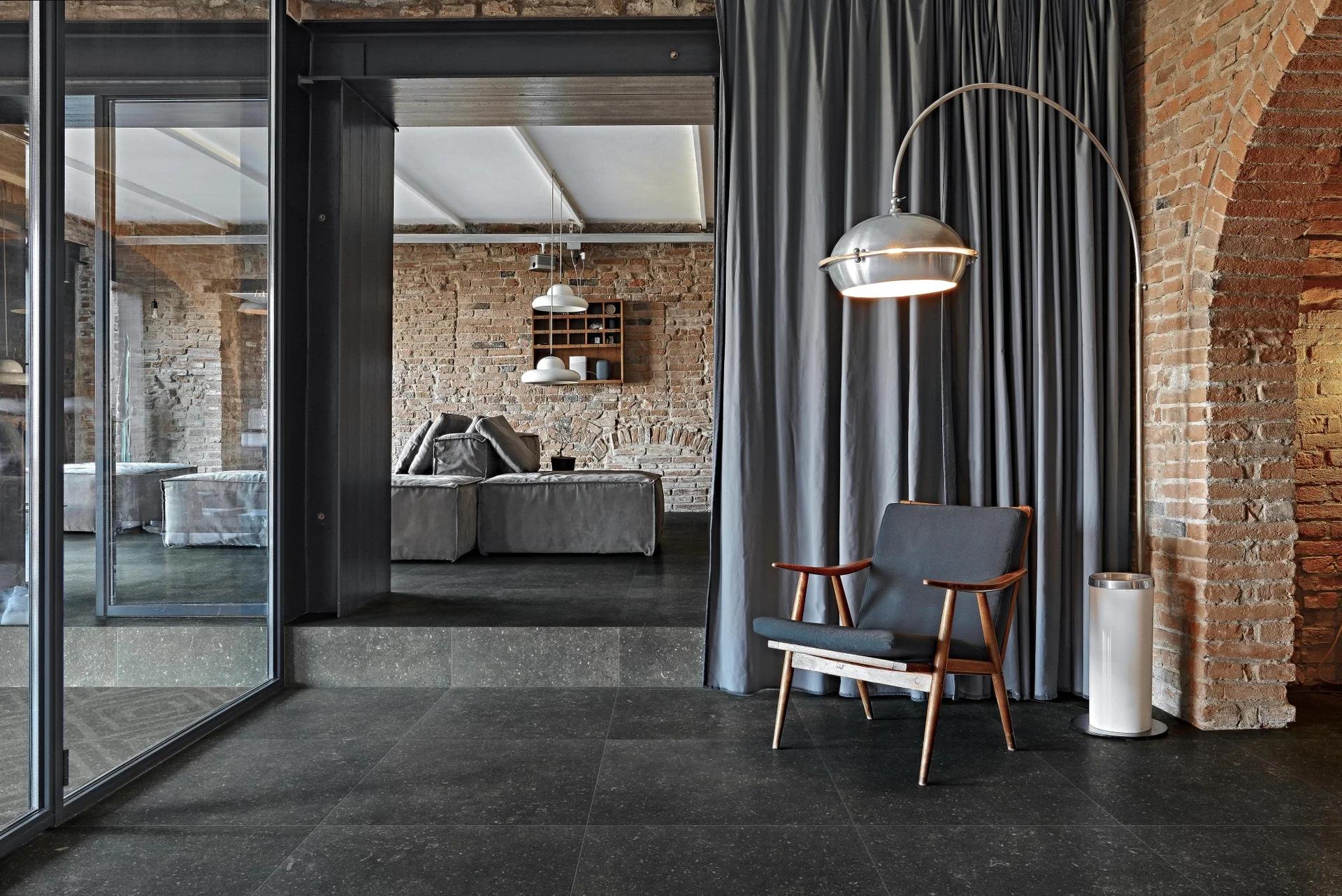 Contemporary industrial living space featuring dark stone-look porcelain floor tiles from the Florim Atmosphères collection, expertly supplied and installed by PietraCasa.