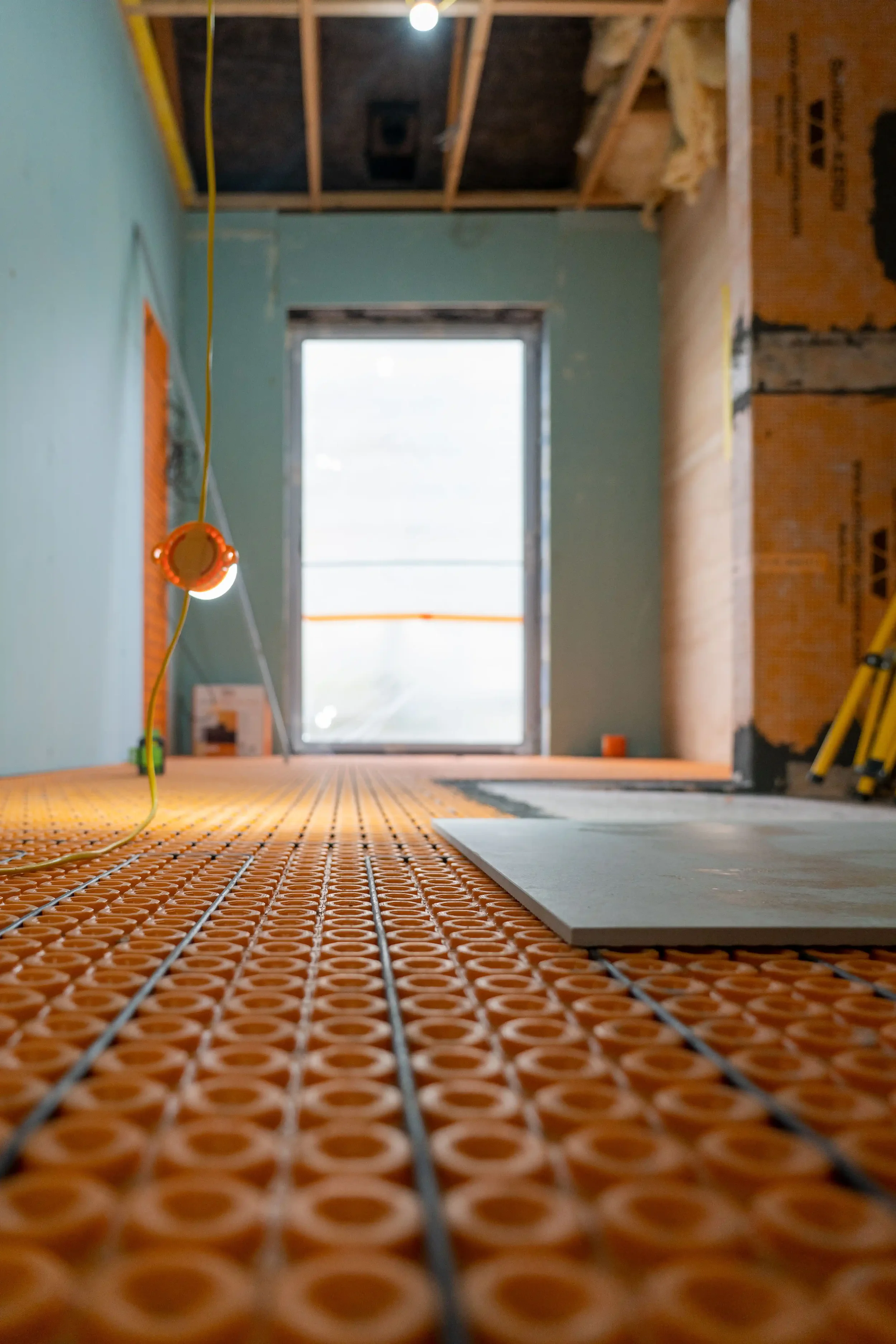 Installation of large-format porcelain floor tiles over a Schluter underfloor heating membrane.