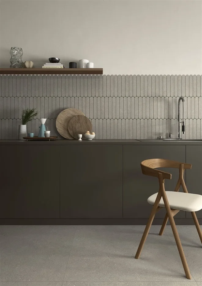 A modern kitchen featuring the Intense collection by Lea Ceramiche, combining minimalist flat-panel cabinets, a natural wood shelf, and organic-shaped tiles, available through PietraCasa.