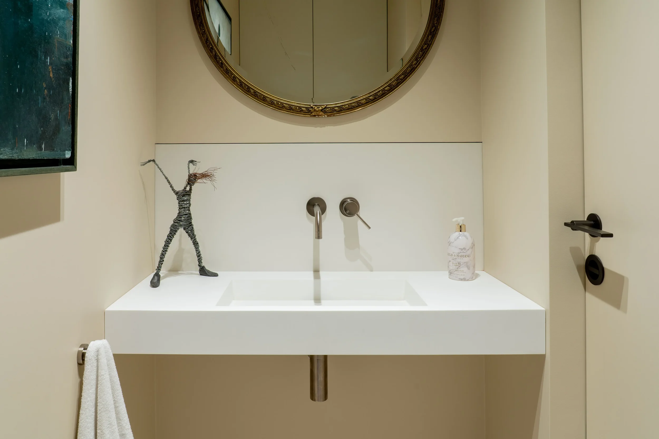 Minimalist cloakroom vanity designed and supplied by Pietracasa and Abitalia, featuring a white Lusso Aura wall-hung stone basin against a low splashback and backdrop of premium Florim porcelain tiles, paired with a sleek wall-mounted brushed steel t