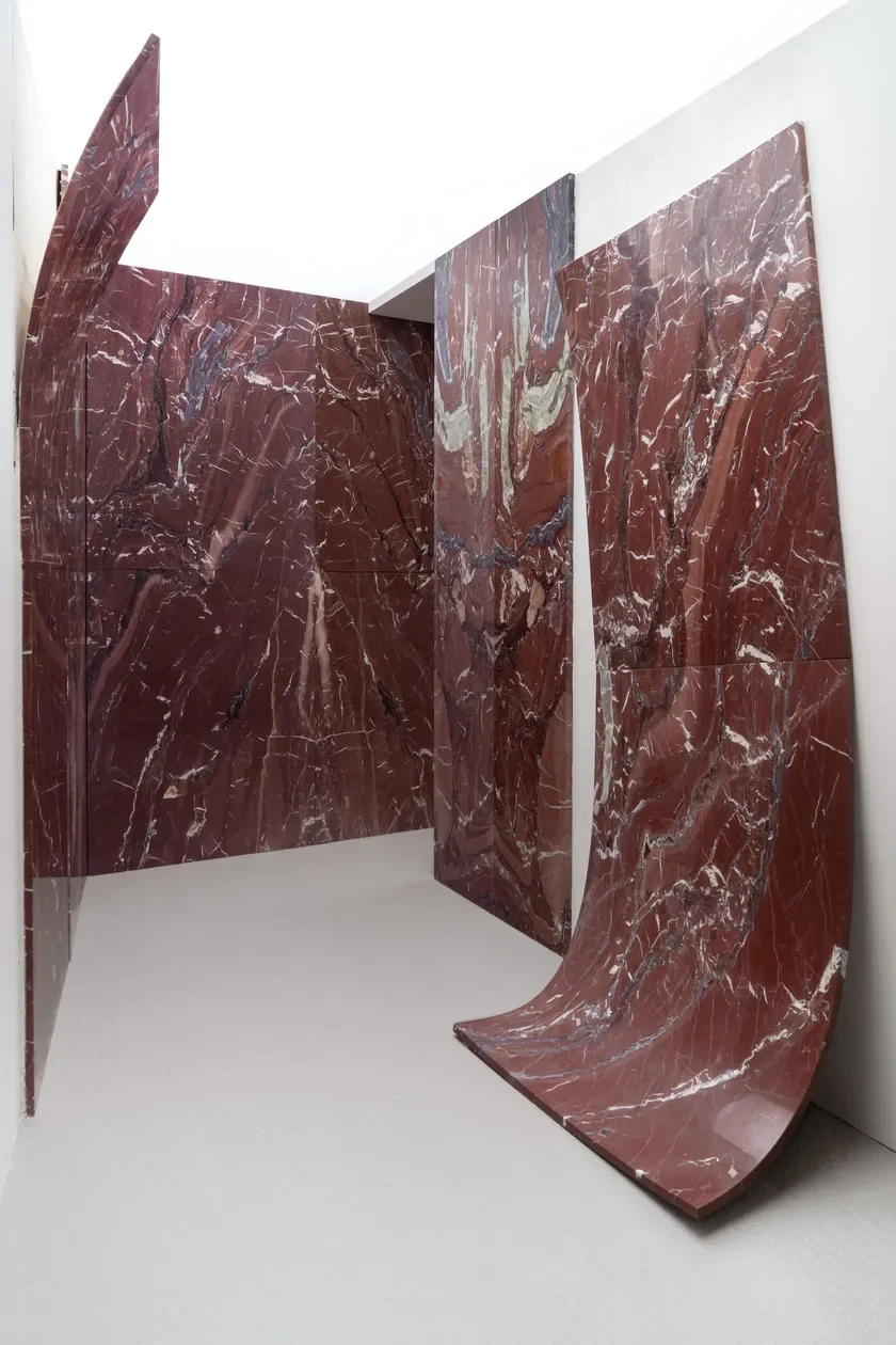 Architectural installation featuring curved slabs of Rosso Cardinale marble by Margraf, highlighting the stone's deep red tones and intricate veining, supplied by PietraCasa.