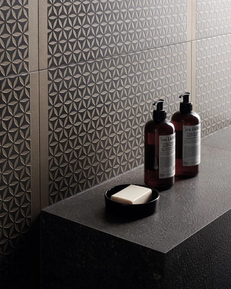 Close-up of a bathroom featuring the Metallique collection by Kronos Ceramiche, showcasing the patterned geometric 'Celtique' decor in the Brune finish alongside a matching metal-look countertop, available through PietraCasa.