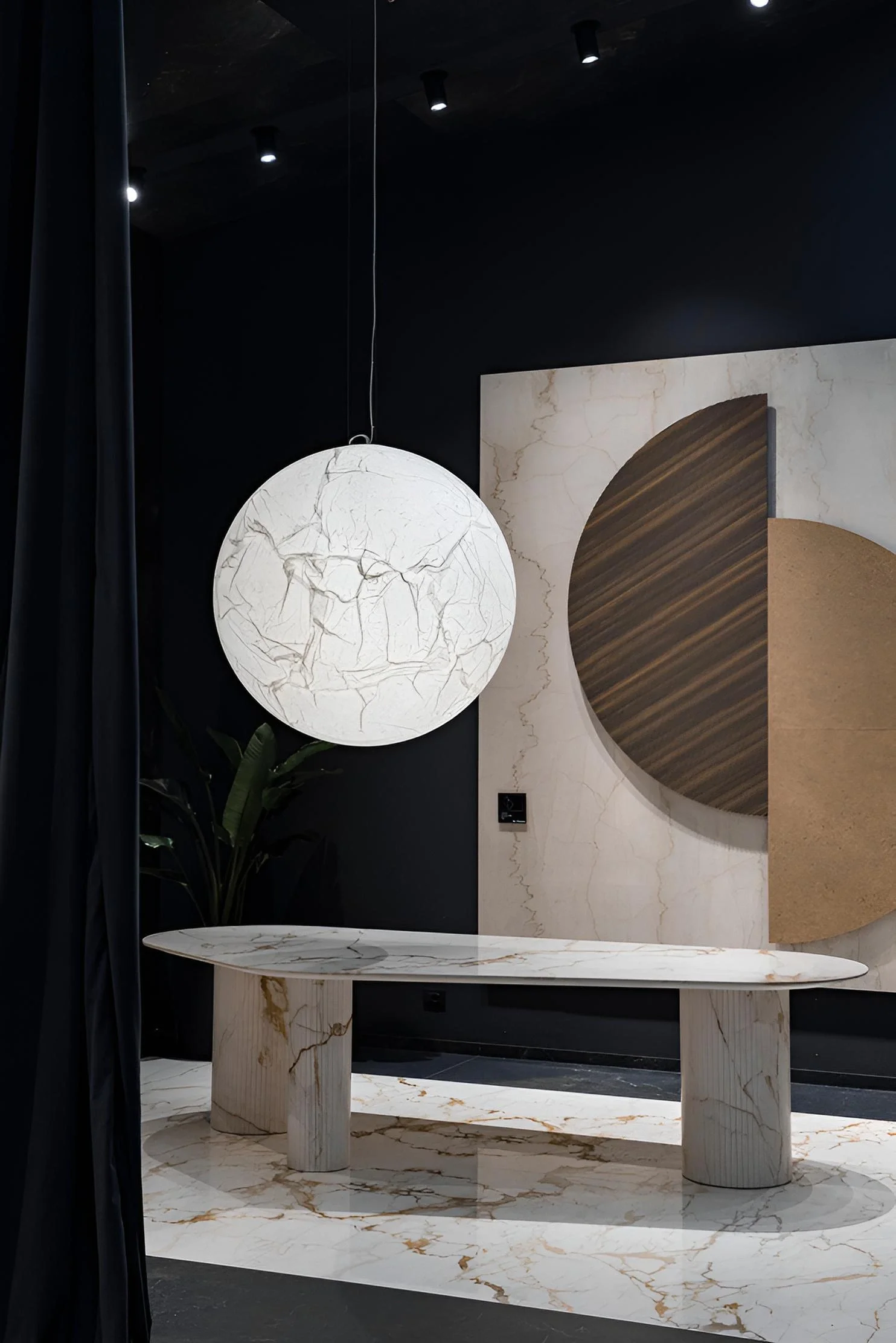 Contemporary installation at Ariostea's 'The Theatre' showroom featuring high-tech porcelain stoneware and the iconic Moon Suspension Lamp designed by Davide Groppi, supplied and installed nationwide by PietraCasa.