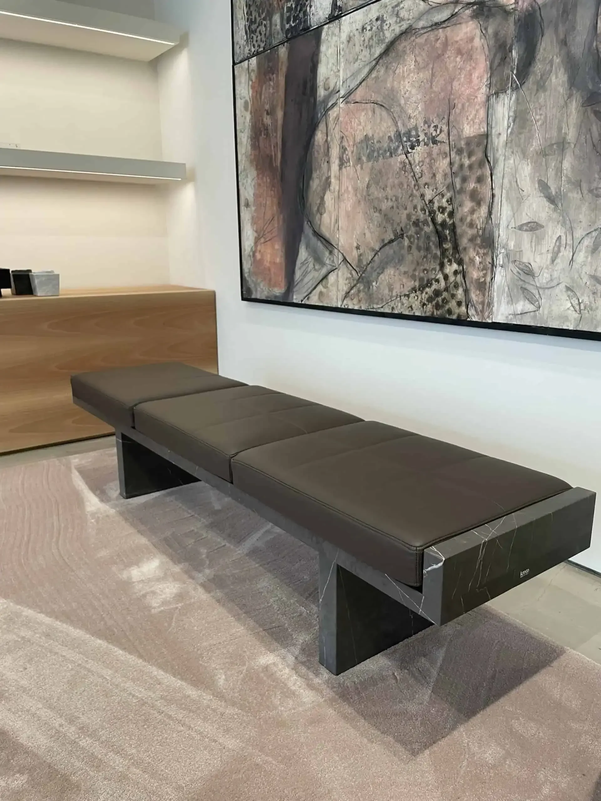 The Ever bench by Kreoo, designed by Christophe Pillet, featuring a structural marble base with a geometric interlocking look and a thick, padded cushion, available through PietraCasa.