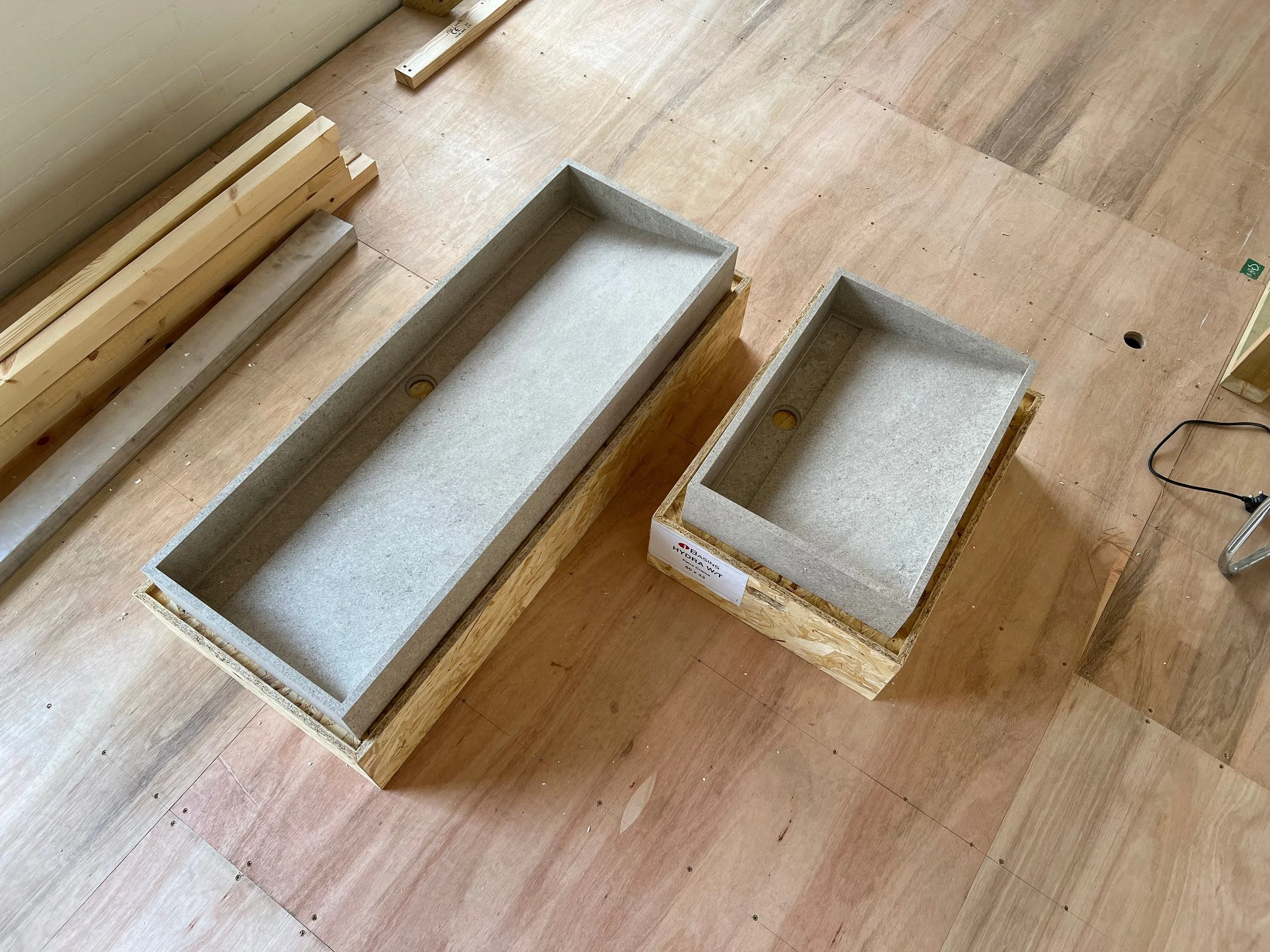 Two new, bespoke stone-effect vanity sinks in different sizes, prepared for installation in a high-end luxury bathroom project.