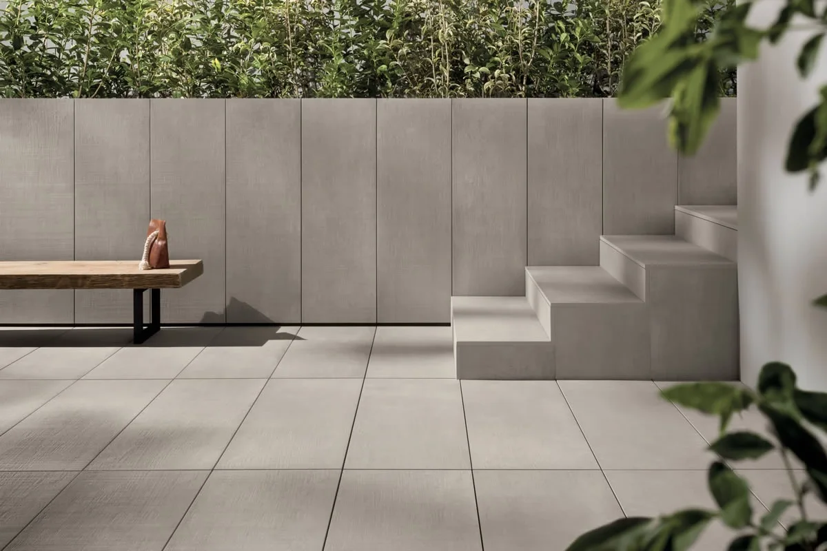 An outdoor space featuring the Prima Materia collection by Kronos Ceramiche, which utilizes Italian porcelain stoneware to create a sleek, concrete-look aesthetic, available through PietraCasa.