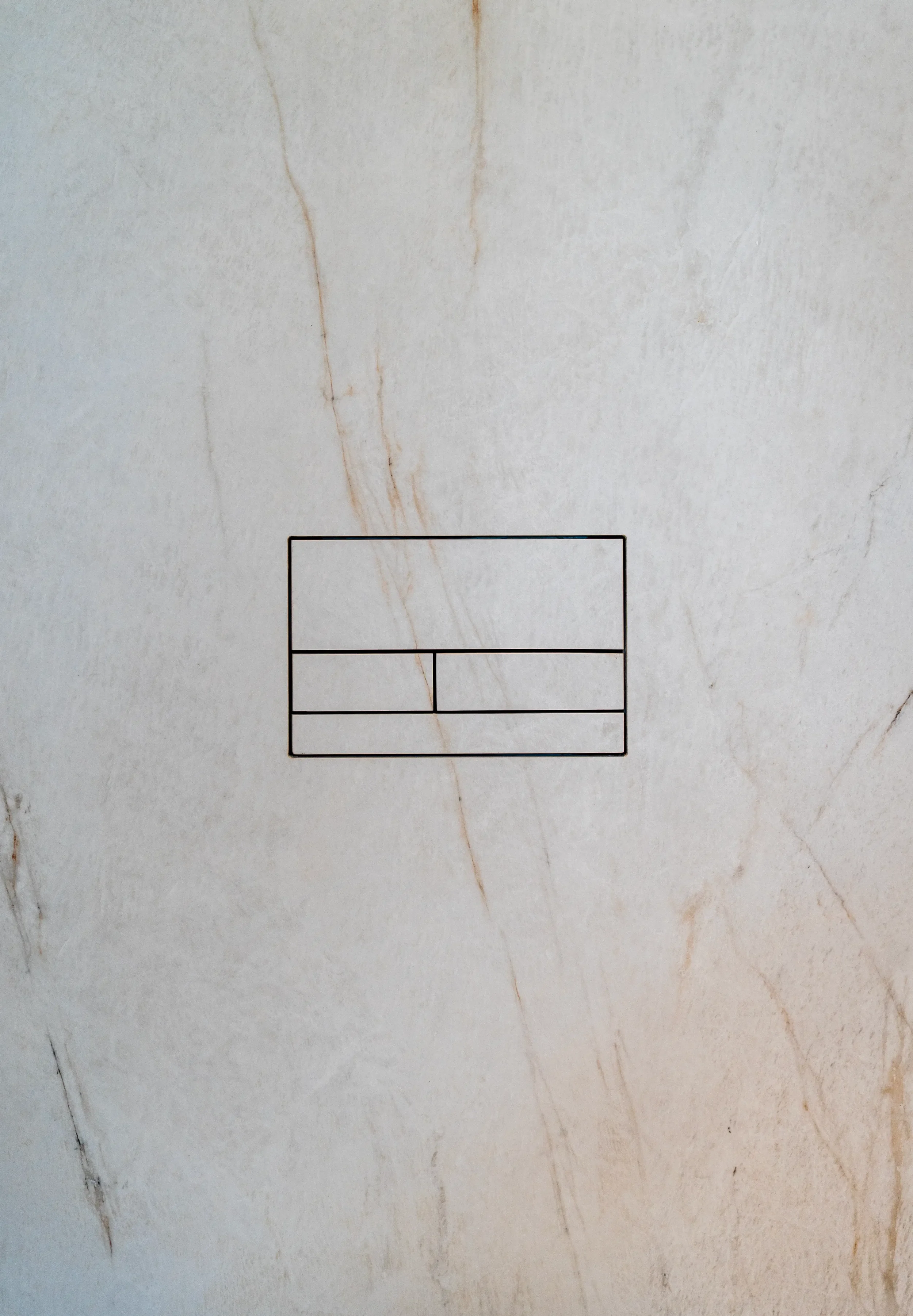 Close-up detail of a minimalist Clanea flush plate seamlessly integrated into high-end porcelain wall tiles, supplied and installed by PietraCasa.