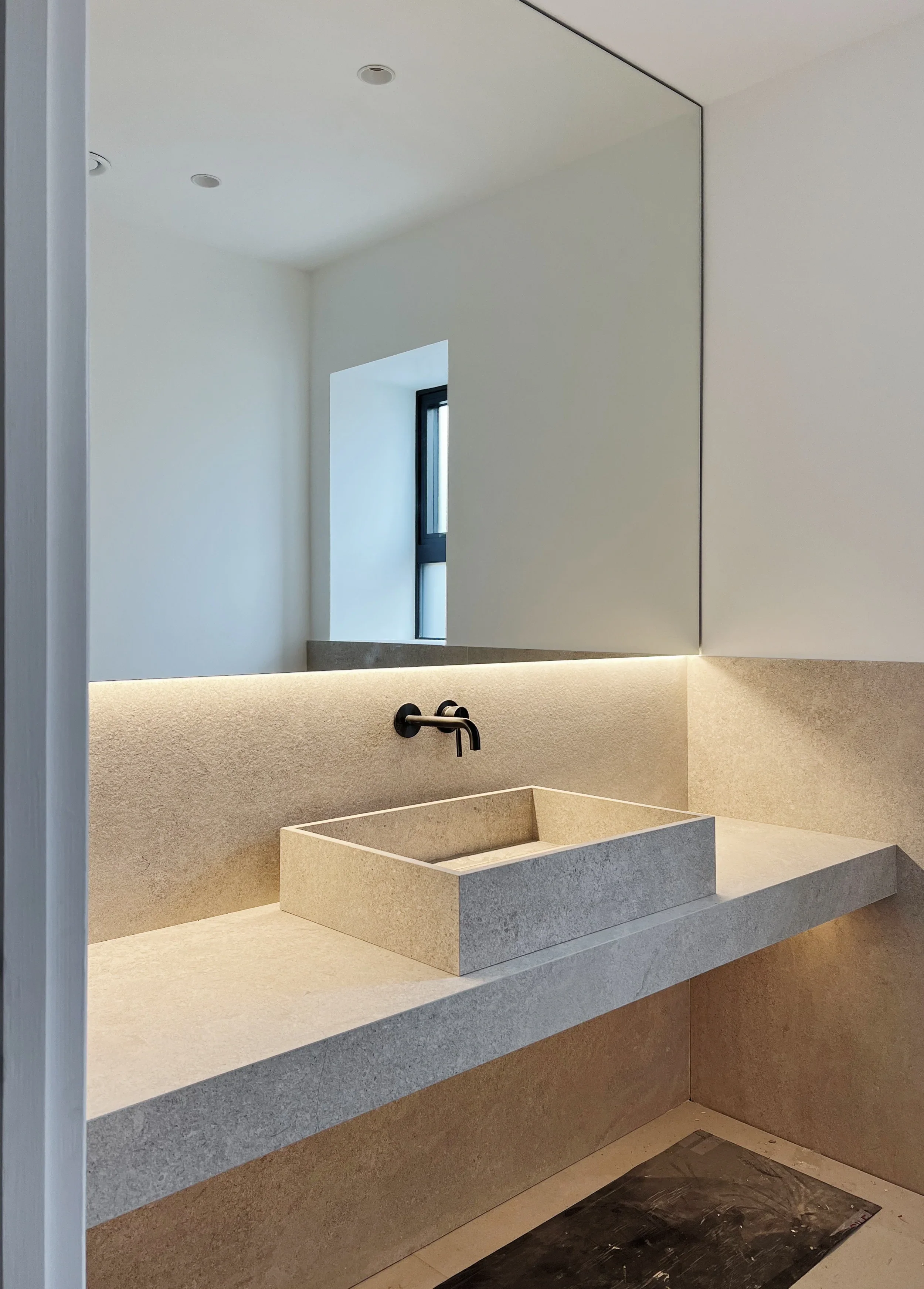 Bespoke floating vanity featuring an integrated vessel basin crafted from beige limestone-effect porcelain by PietraCasa.