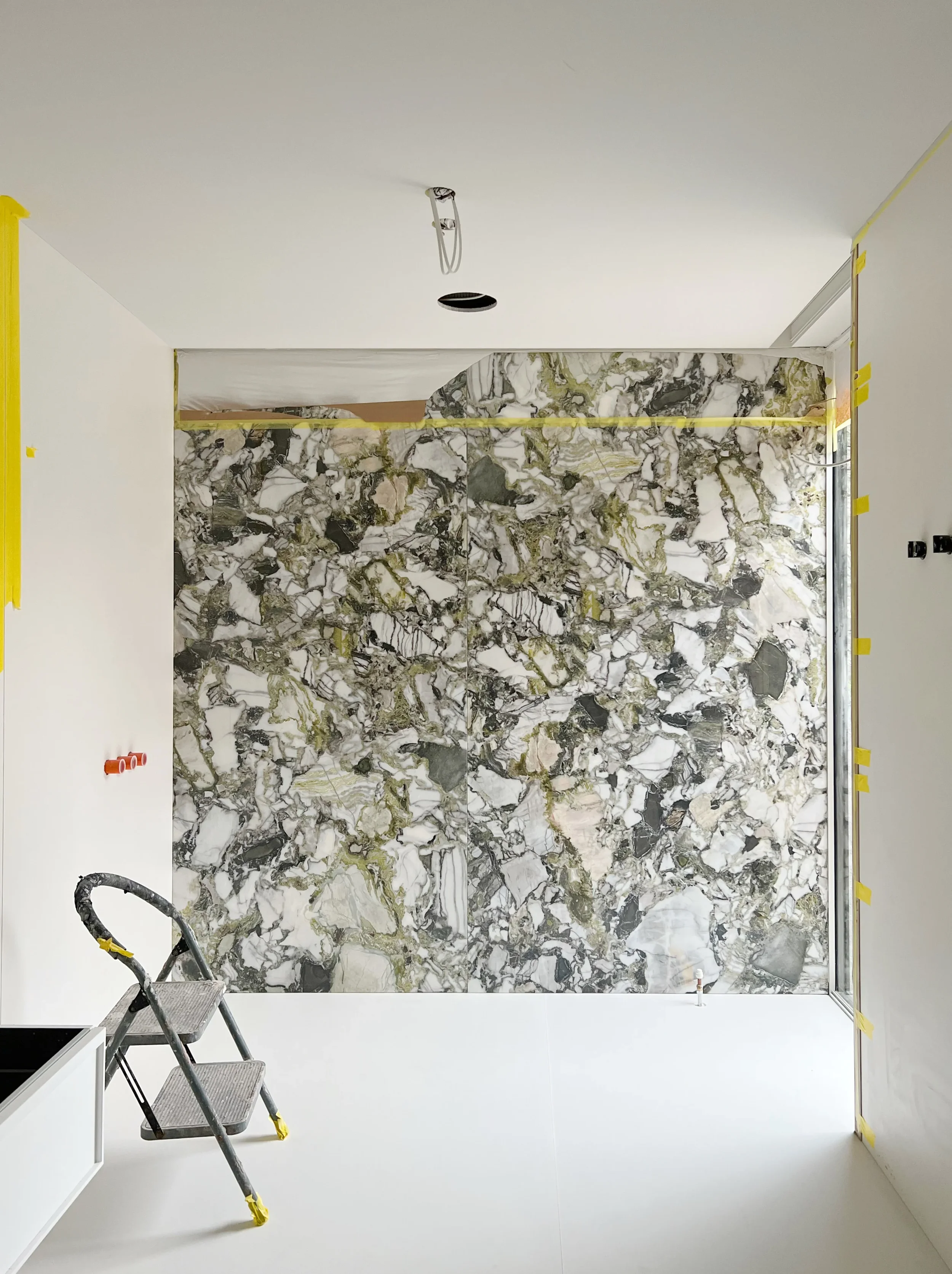A high-end interior installation featuring a bespoke-fabricated, marble-effect porcelain feature wall. The design showcases precision joinery and seamless material integration.