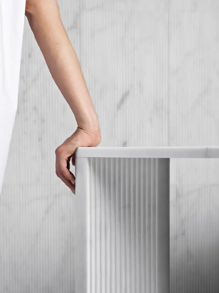 The Overlay Console Table by Luce di Carrara, a luxury Italian design crafted entirely from natural stone with a signature 3D-fluted texture on its base and rounded edges, available through PietraCasa.