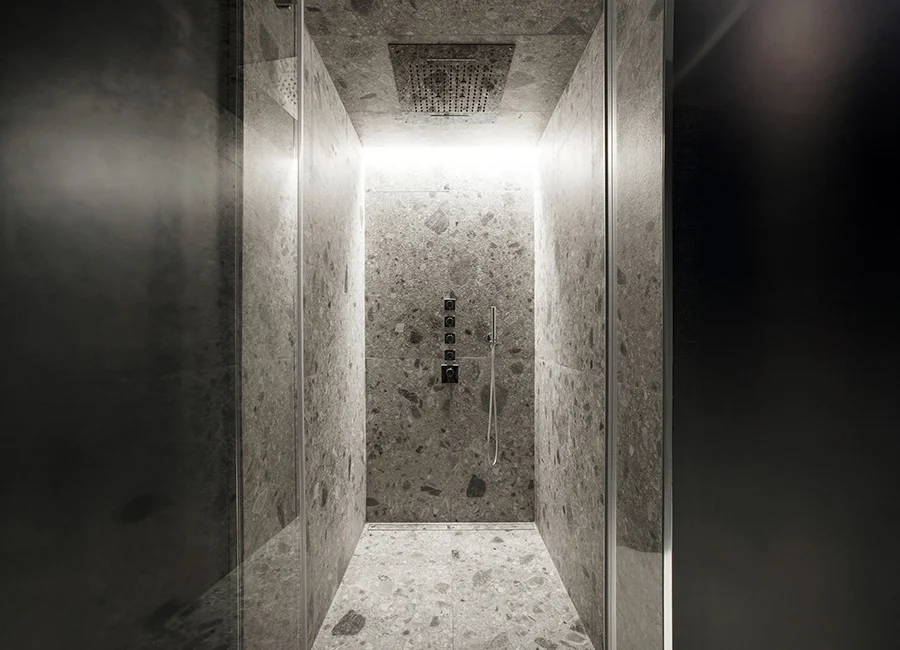 Luxurious modern walk-in shower lined with Inalco Iseo Gris ceramic surfaces, a sintered stone material mimicking conglomerate and terrazzo rocks, exclusively distributed in the UK by PietraCasa.