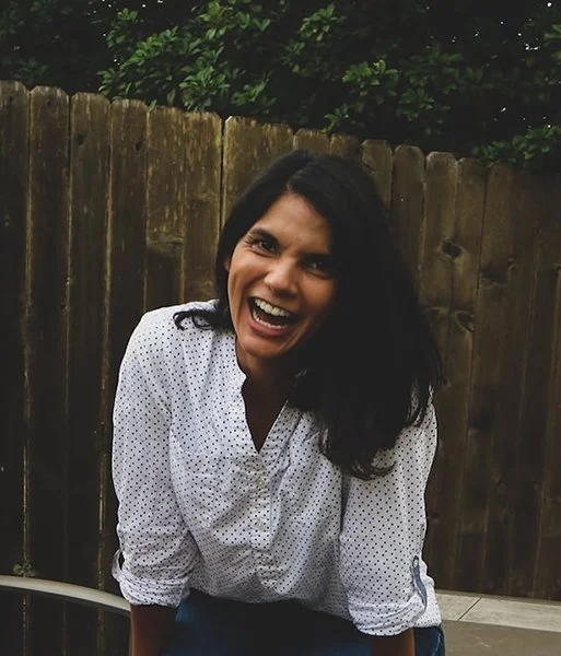 Headshot of Laura Niebauer, Career Coach, laughing in front of fence