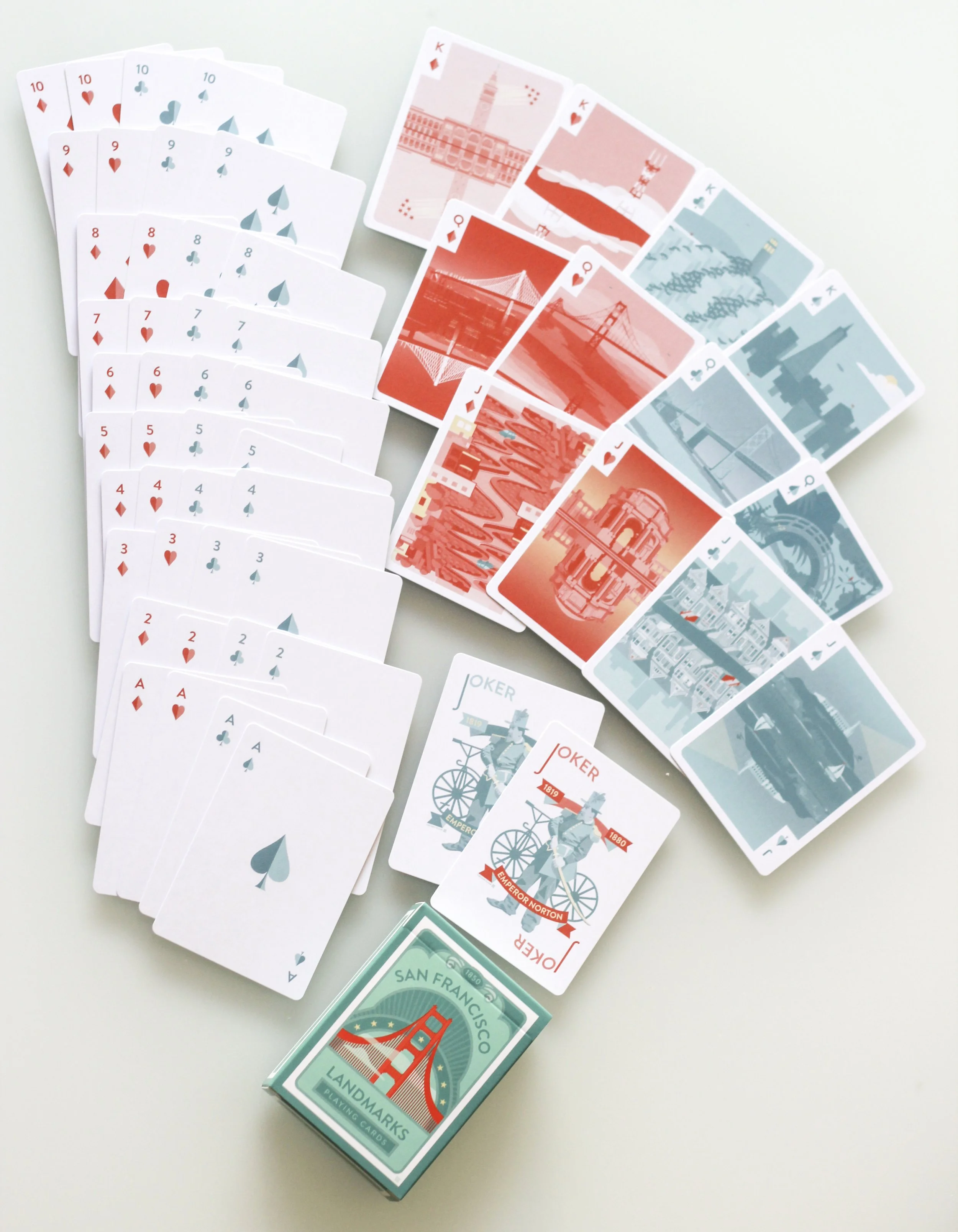 A spread of playing cards from a deck featuring iconic San Francisco landmarks in red and blue designs, including the Golden Gate Bridge and the Transamerica Pyramid.