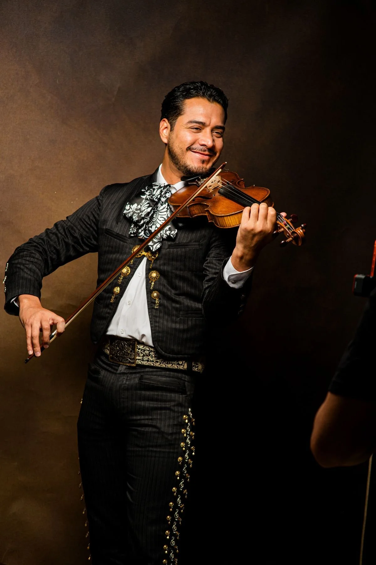 A man dressed in traditional mariachi attire playing the violin.