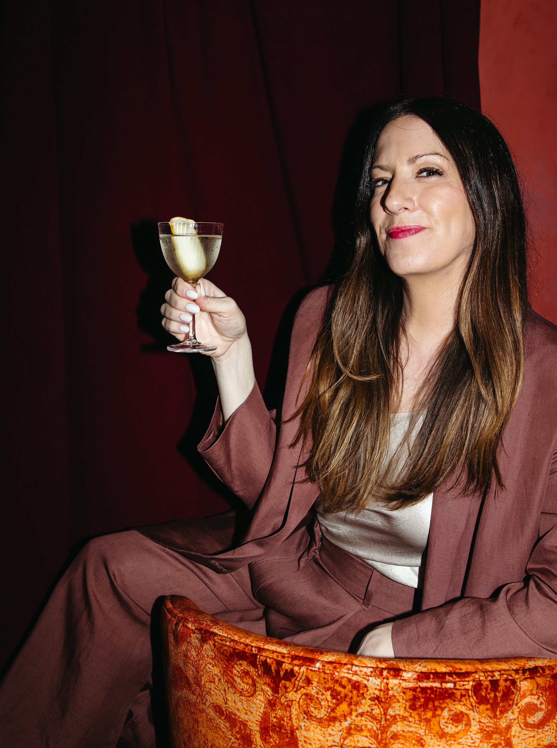 Kristin Mitchell seated in an ornate chair, holding a champagne glass