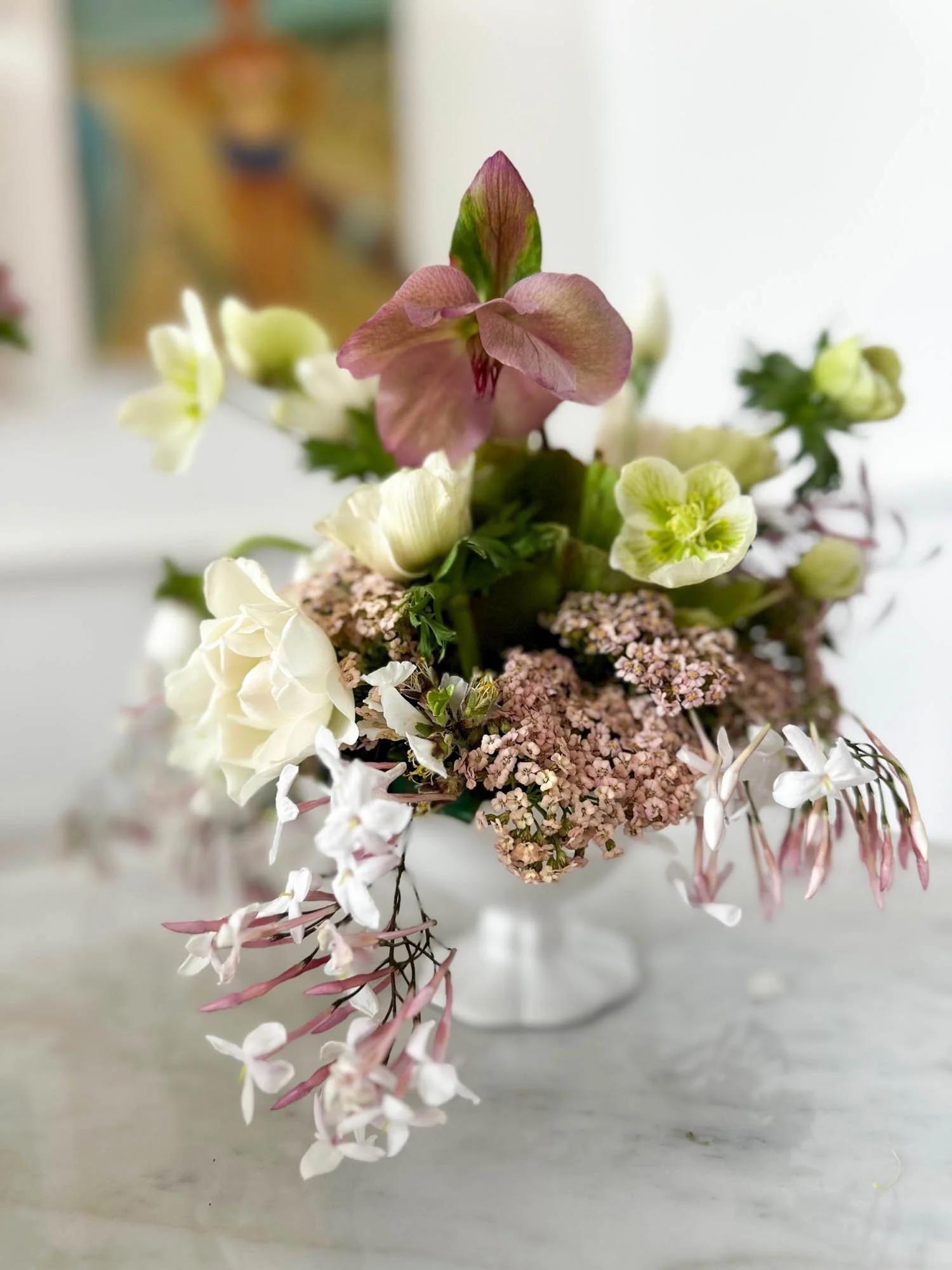 A close-up of a mixed flower bouquet featuring pink, white, and green flowers, with a blurred background.