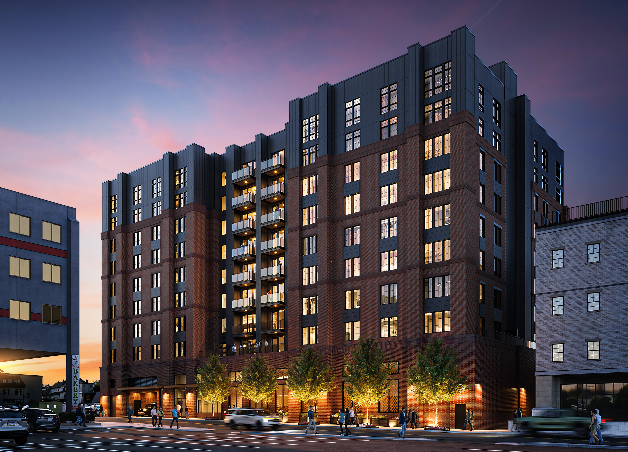 A multi-story modern residential building with brick and metal exterior, lit windows, and balconies, during twilight with people walking on the sidewalk and cars parked in front.