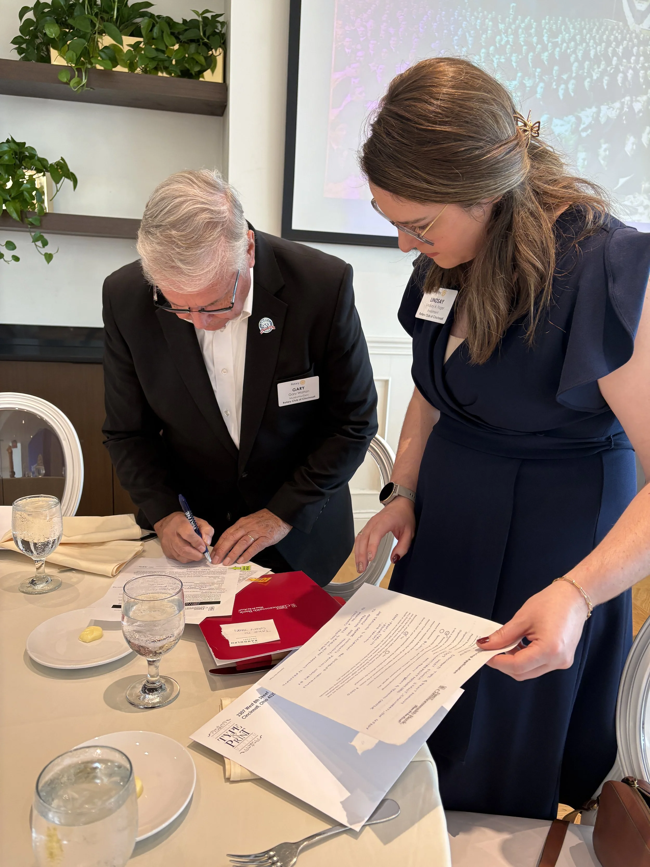 two people at business lunch signing papers