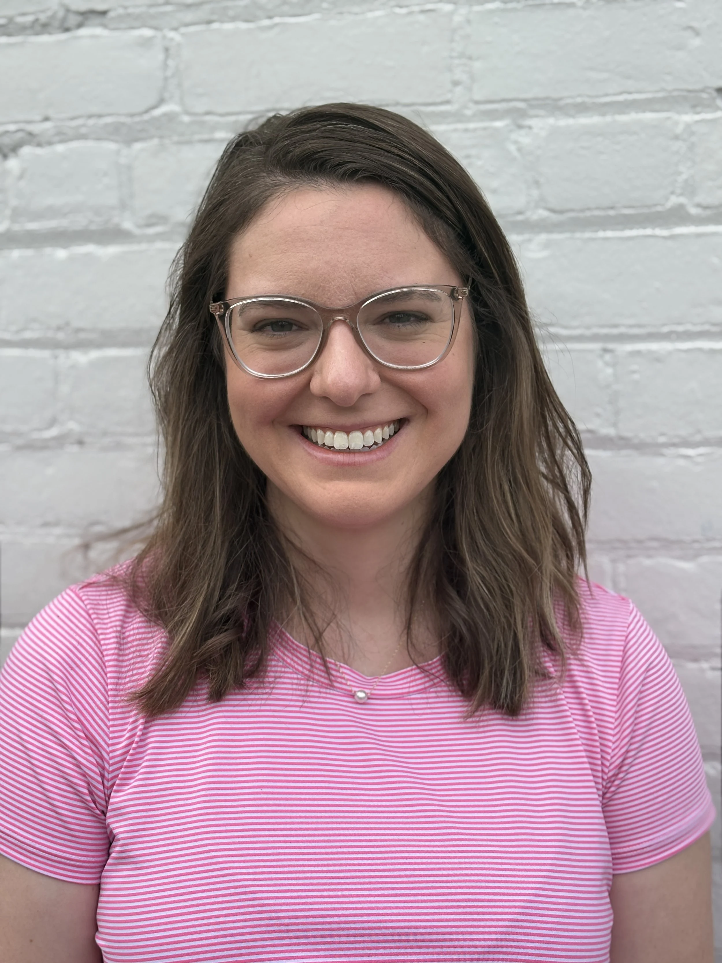 woman in pink dress and glasses smiling