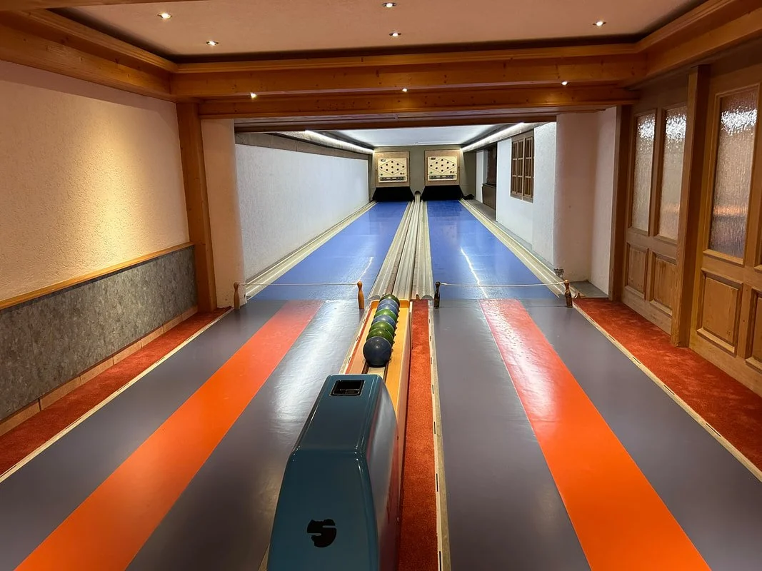 Indoor bowling alley with two lanes and a row of bowling balls at the start