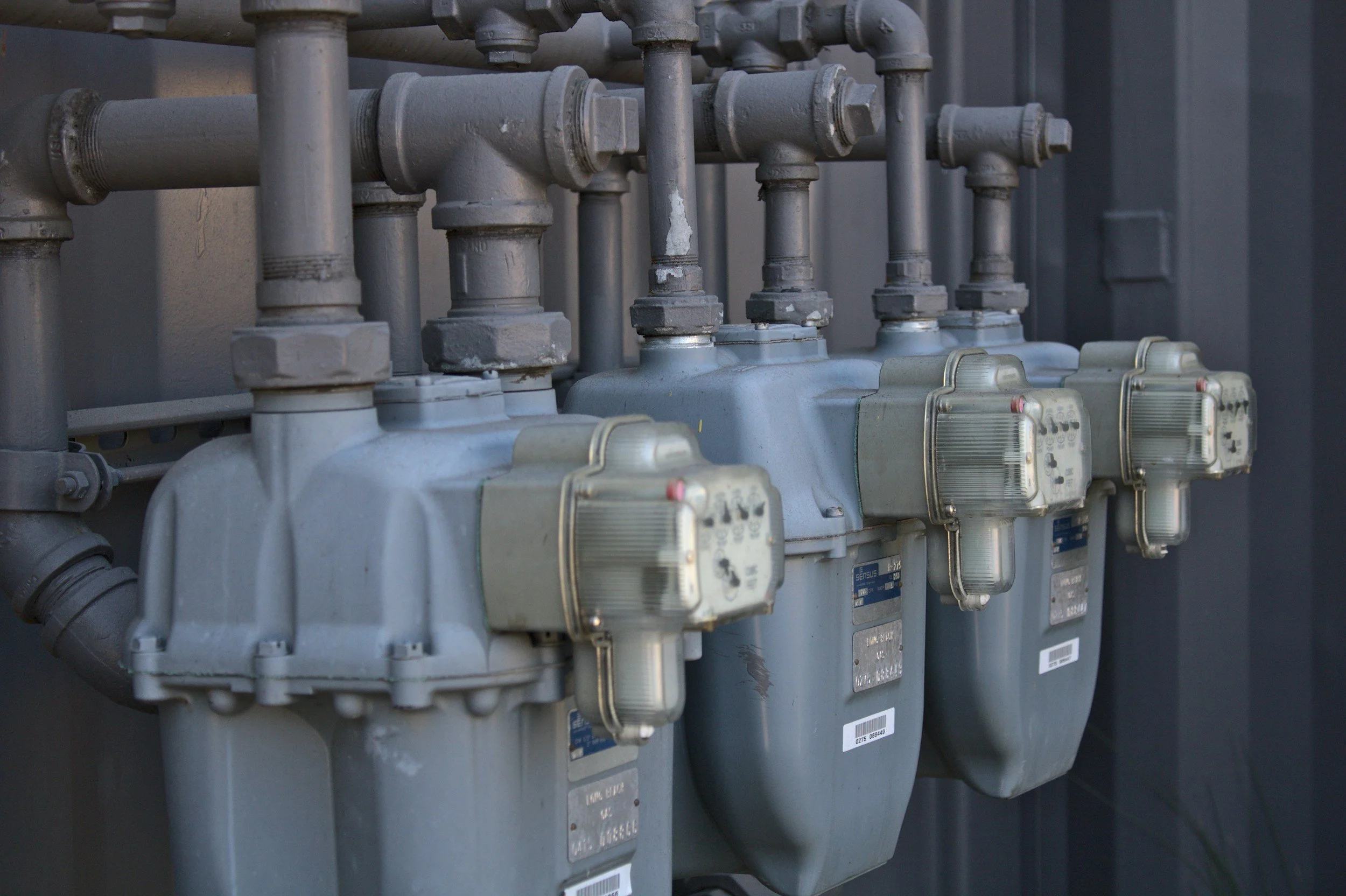 Industrial meters with pipes and valves mounted on a wall.