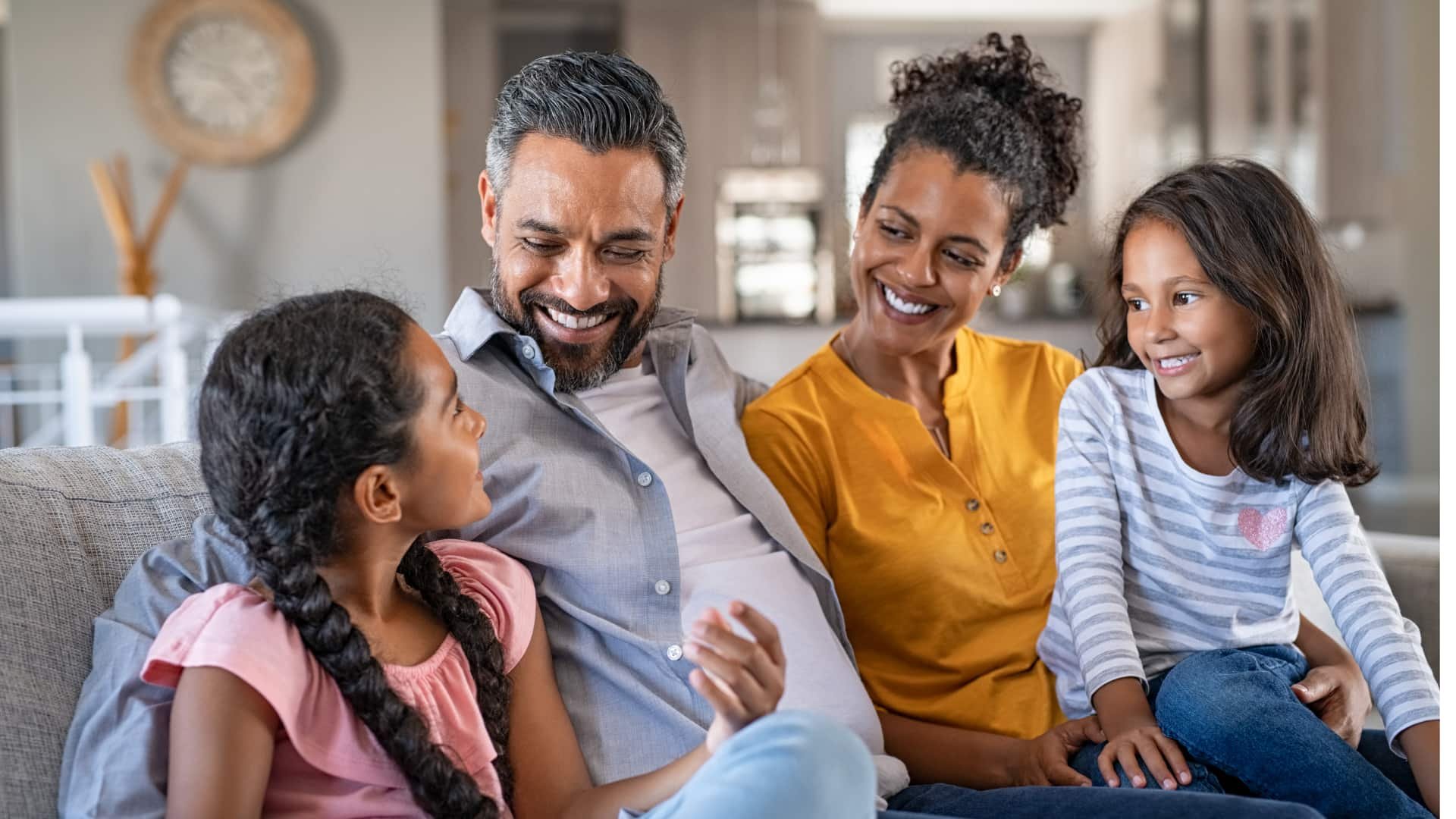 Family sitting on the couch smiling in a clean home