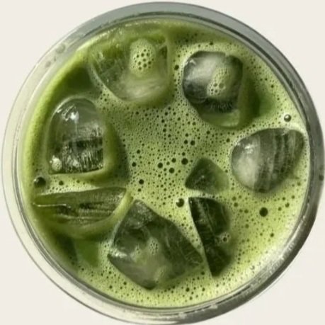 Glass filled with a green drink and ice cubes.