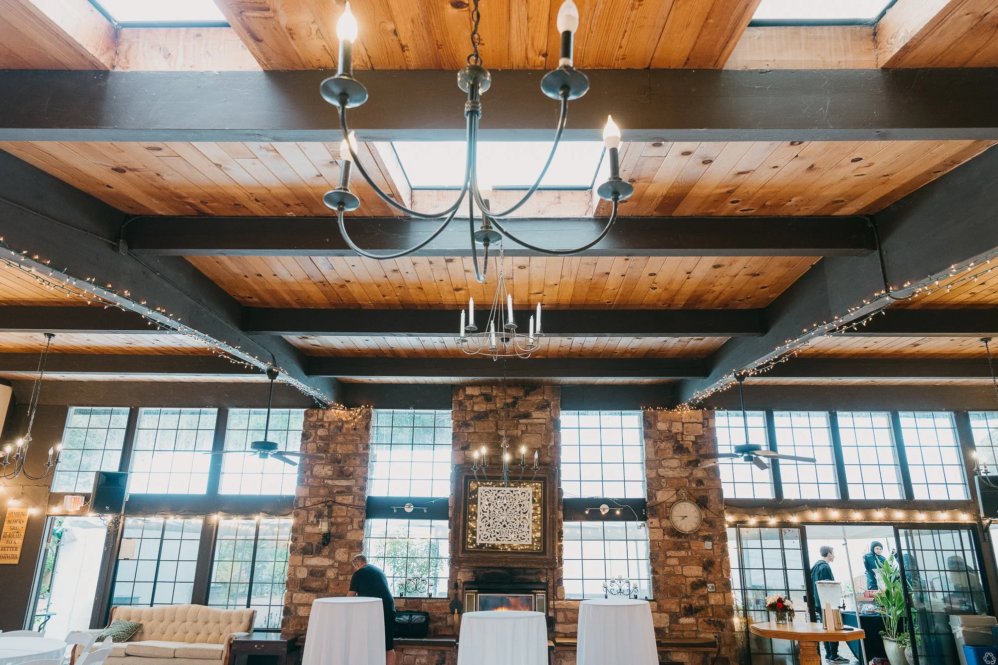 Clubhouse interior with wood-beam ceiling, chandelier and stone fireplace at Wildwood Acres
