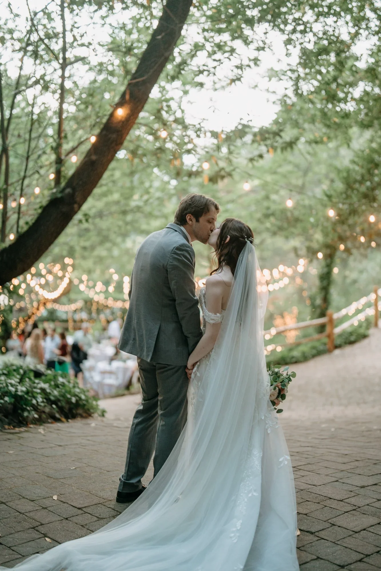 Bride and groom kissing under string lights