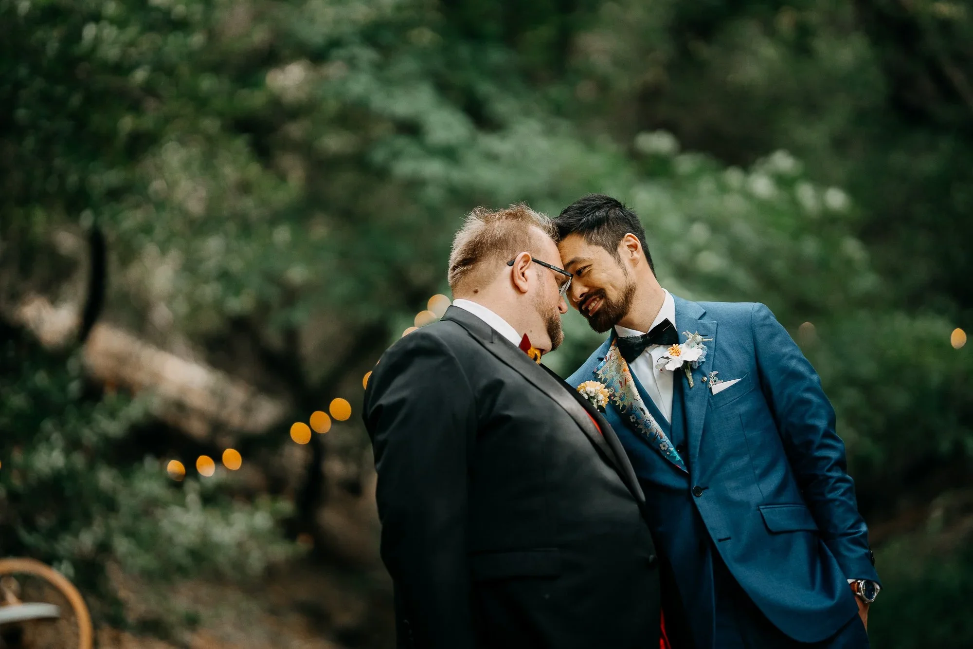 Grooms sharing a tender moment in the woods