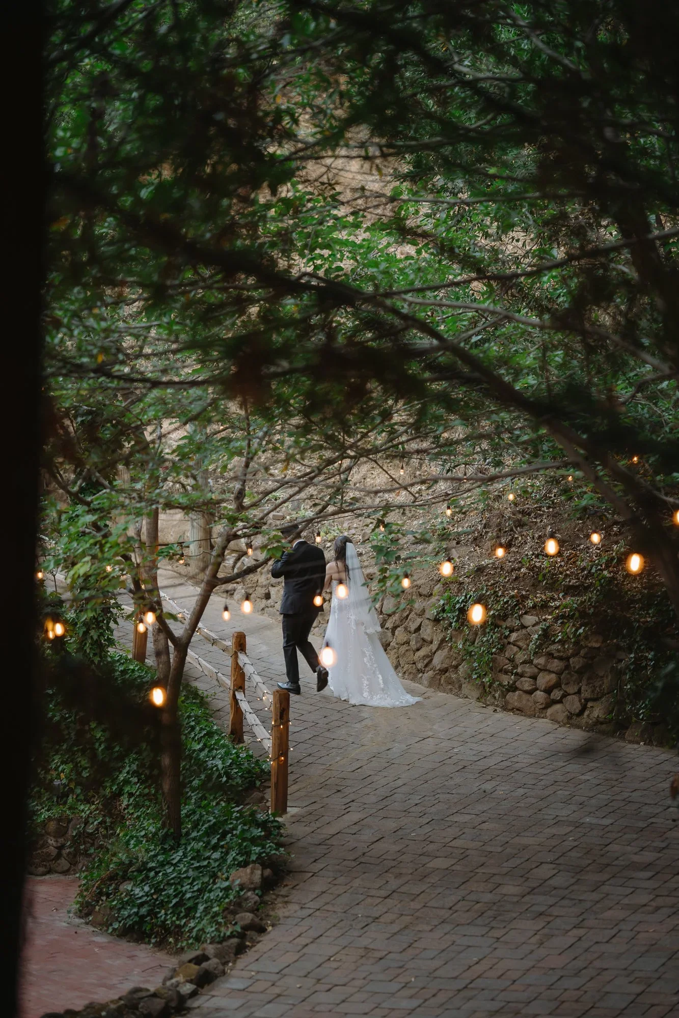 Newlyweds walking beneath the string lights