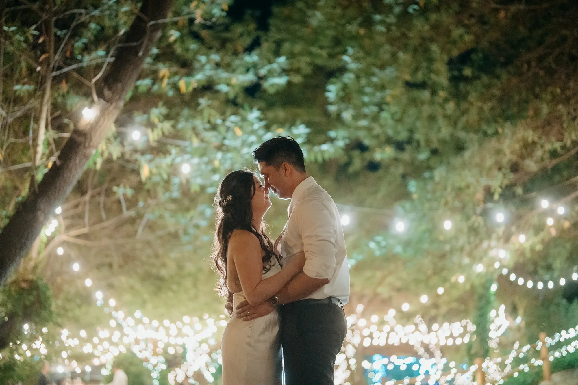 Couple embracing beneath glowing lights