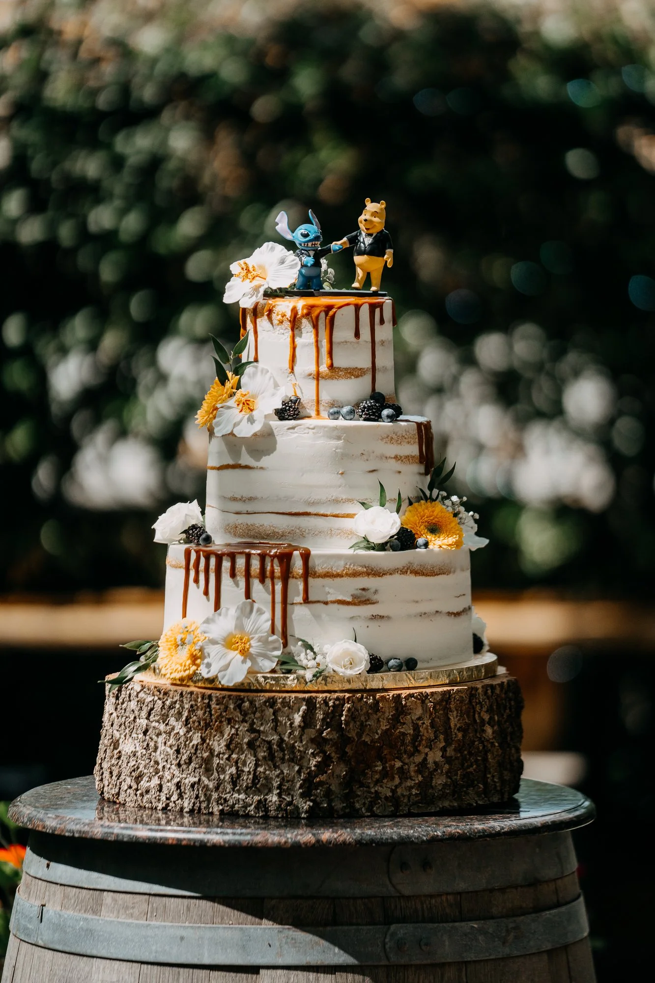 Semi-naked wedding cake with caramel drip and fresh flowers at Wildwood Acres