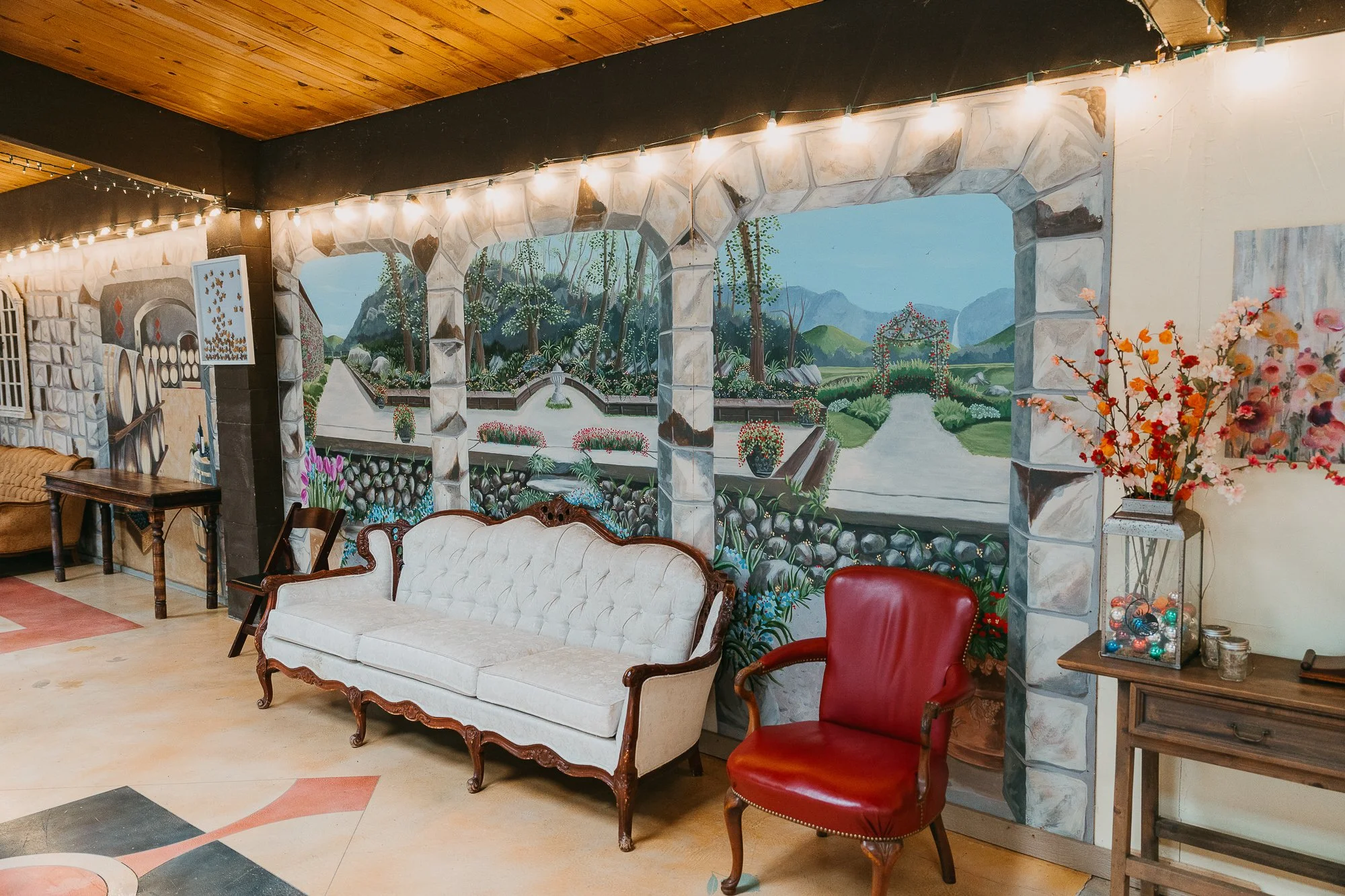 Lounge area with white tufted sofa and garden mural at Wildwood AcresBridal lounge with white tufted sofa and garden mural at Wildwood Acres