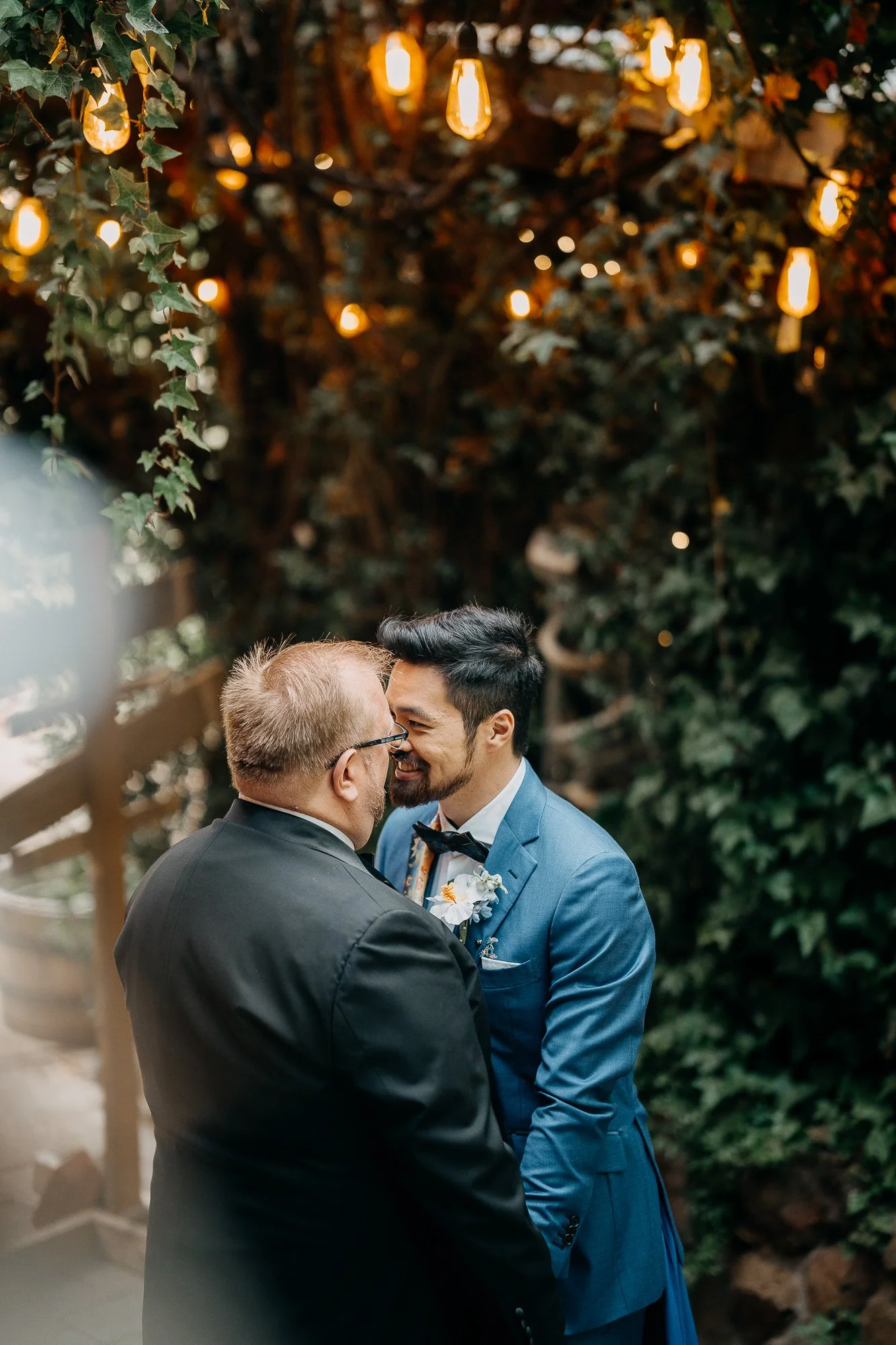 Two grooms embracing under the trees at Wildwood Acres
