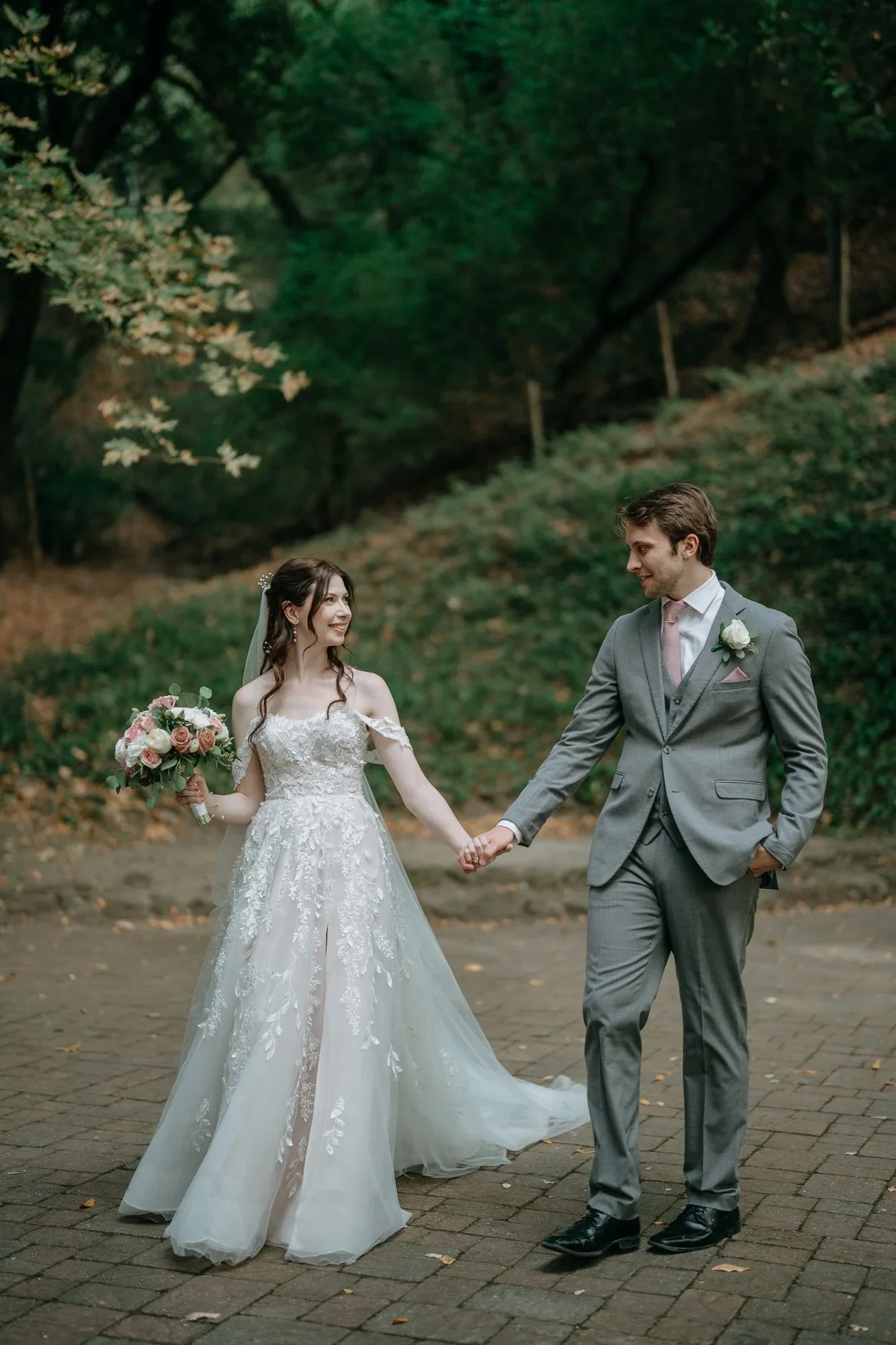 Bride and groom holding hands on a wooded path