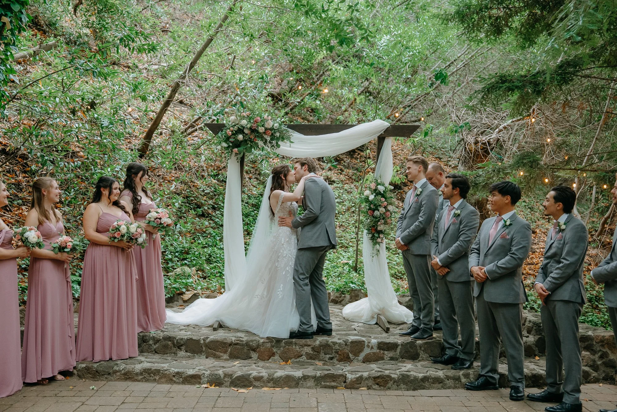 First kiss at the wooded ceremony site at Wildwood Acres