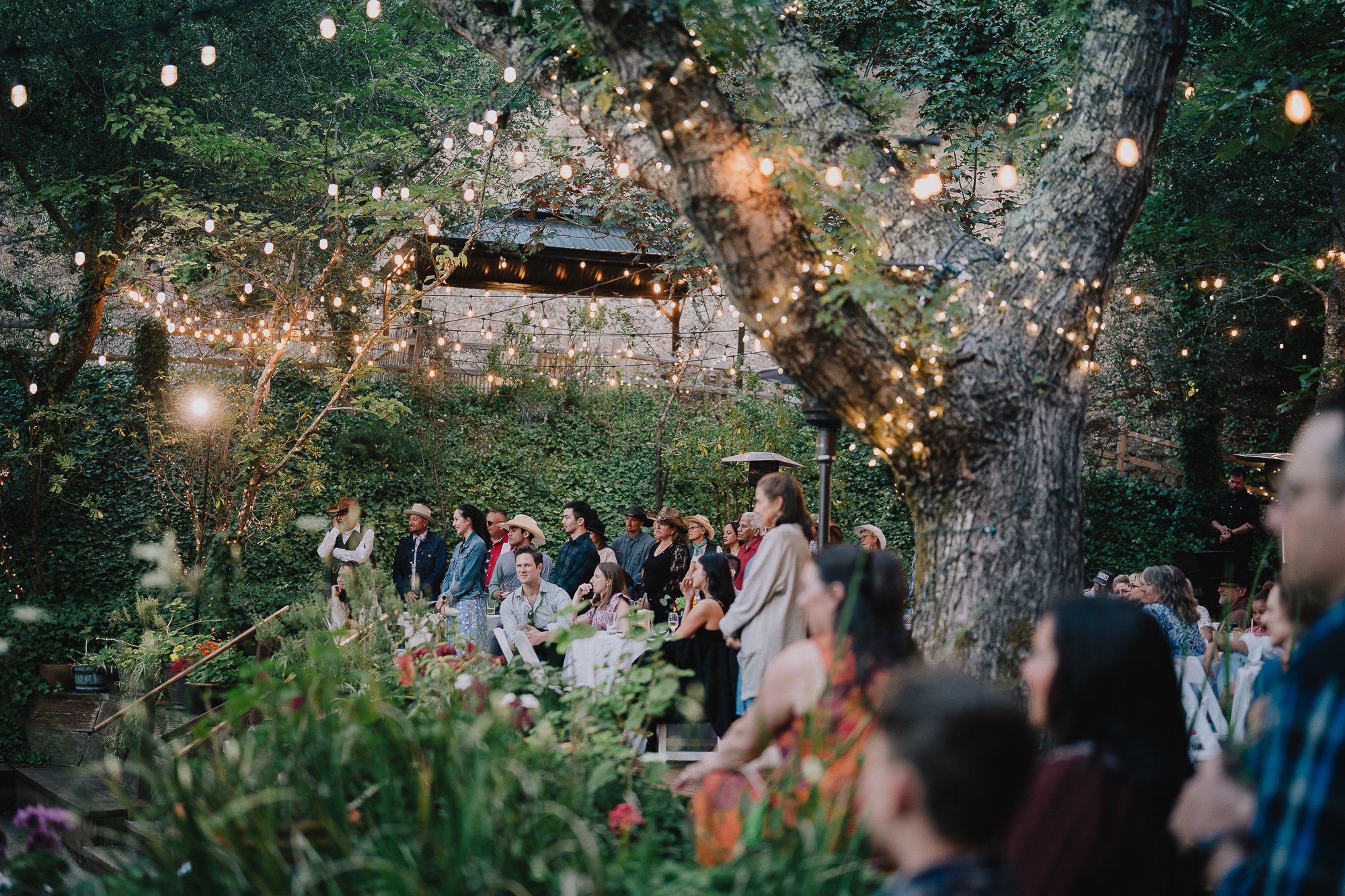 Guests seated for an outdoor ceremony under string lights