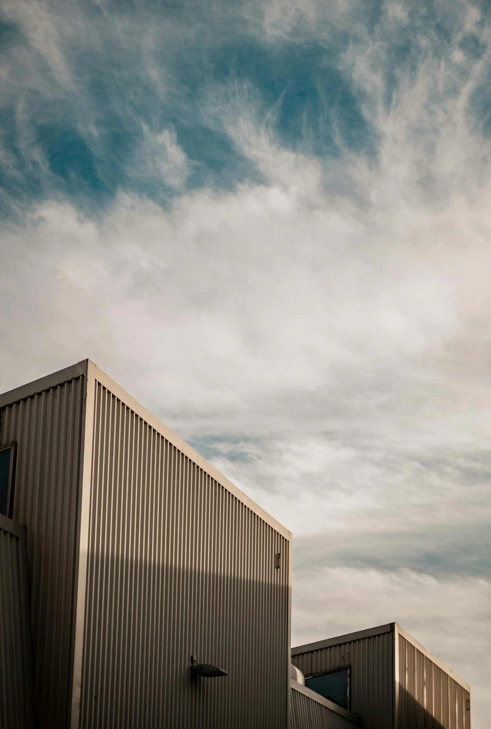 Modern metallic buildings with a cloudy sky in the background.