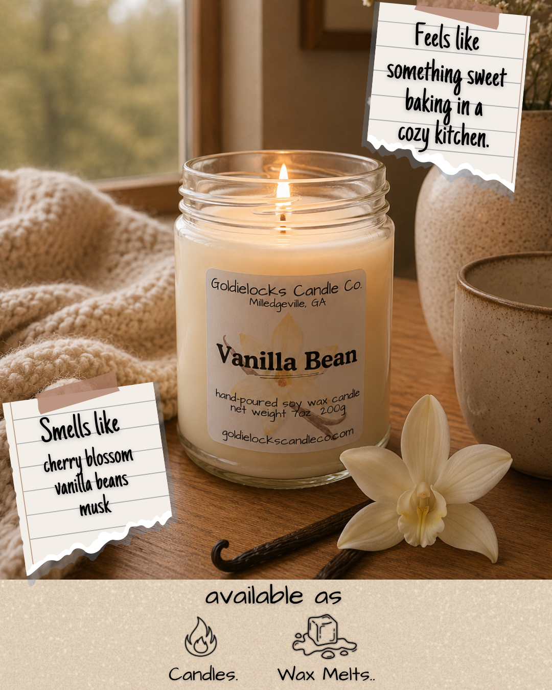A lit vanilla bean scented candle in a glass jar with a label from Goldielocks Candle Co. sits on a wooden surface beside vanilla beans, a white orchid, and two ceramic bowls, with notes indicating it smells like cherry blossom, vanilla beans, and musk, and is available as candles and wax melts.