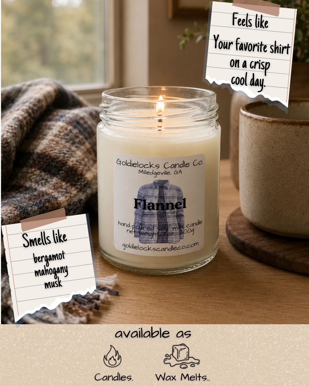 A lit vanilla scented candle from Goldielocks Candle Co., Milledgville, Georgia, in a glass jar, placed on a wooden surface next to a mug and a blanket, with notes describing it as feeling like wearing a favorite shirt on a cool day and smelling like bergamot, mahogany, and musk. Text at the bottom indicates the candle is available as candles or wax melts.