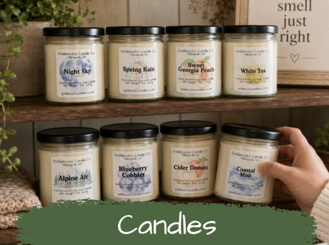Collection of eight candles in glass jars with black lids, labeled with various scents, on wooden shelves.