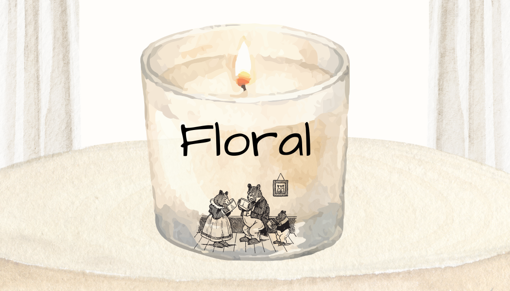 A lit floral scented candle in a glass container with a drawing of four bear characters reading, titled 'Floral,' on a white surface with a textured background.