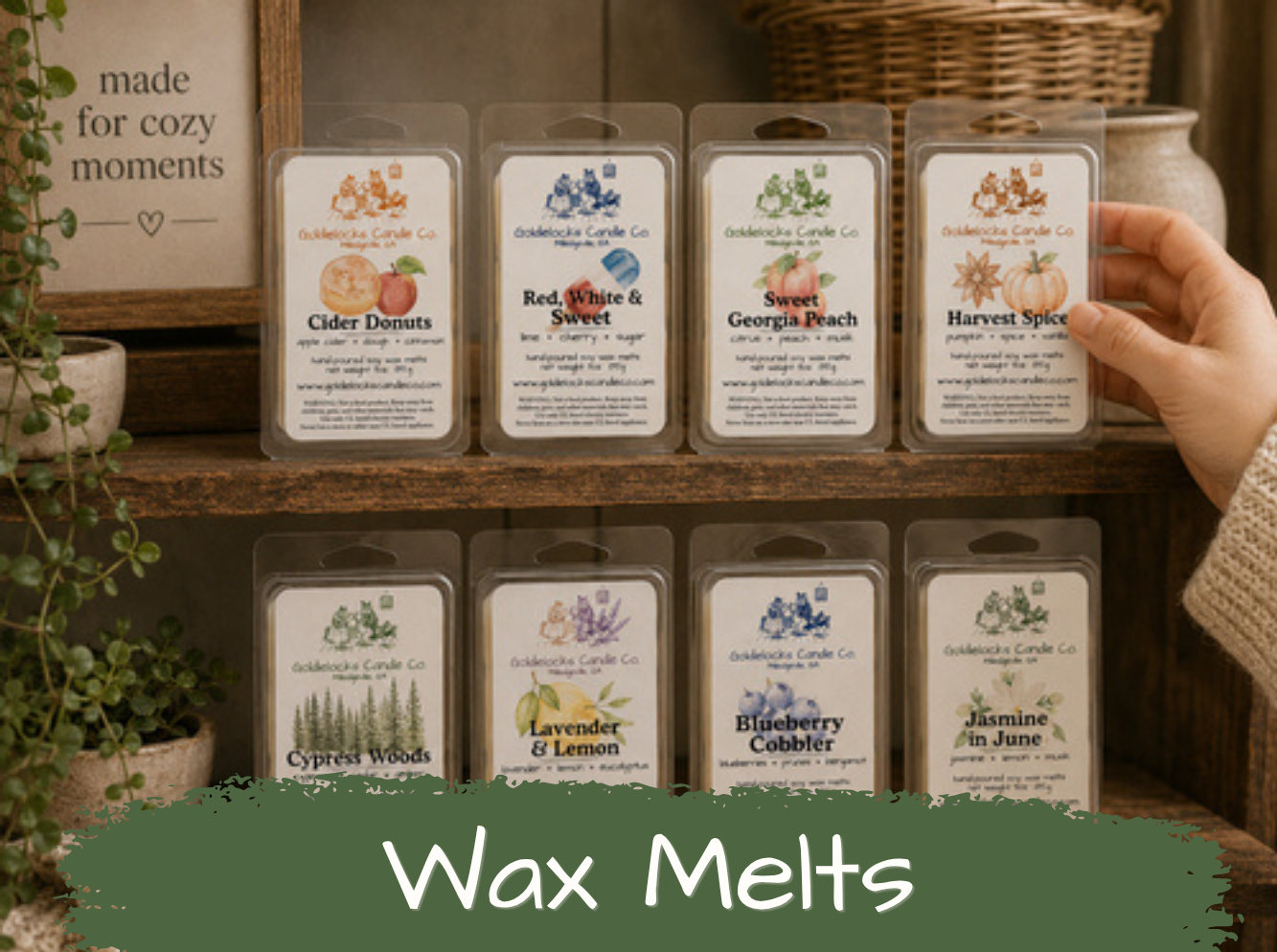 Display of wax melts in clear plastic containers with decorative labels, arranged on a wooden shelf. Labels feature images of pumpkins, peaches, spices, and herbs with scents like Cider Donuts, Red, White & Sweet, Georgia Peach, Harvest Spice, Cypress Woods, Lavender & Lemon, Blueberry Cobbler, and Jasmine in June. A hand holds one container on the right side.