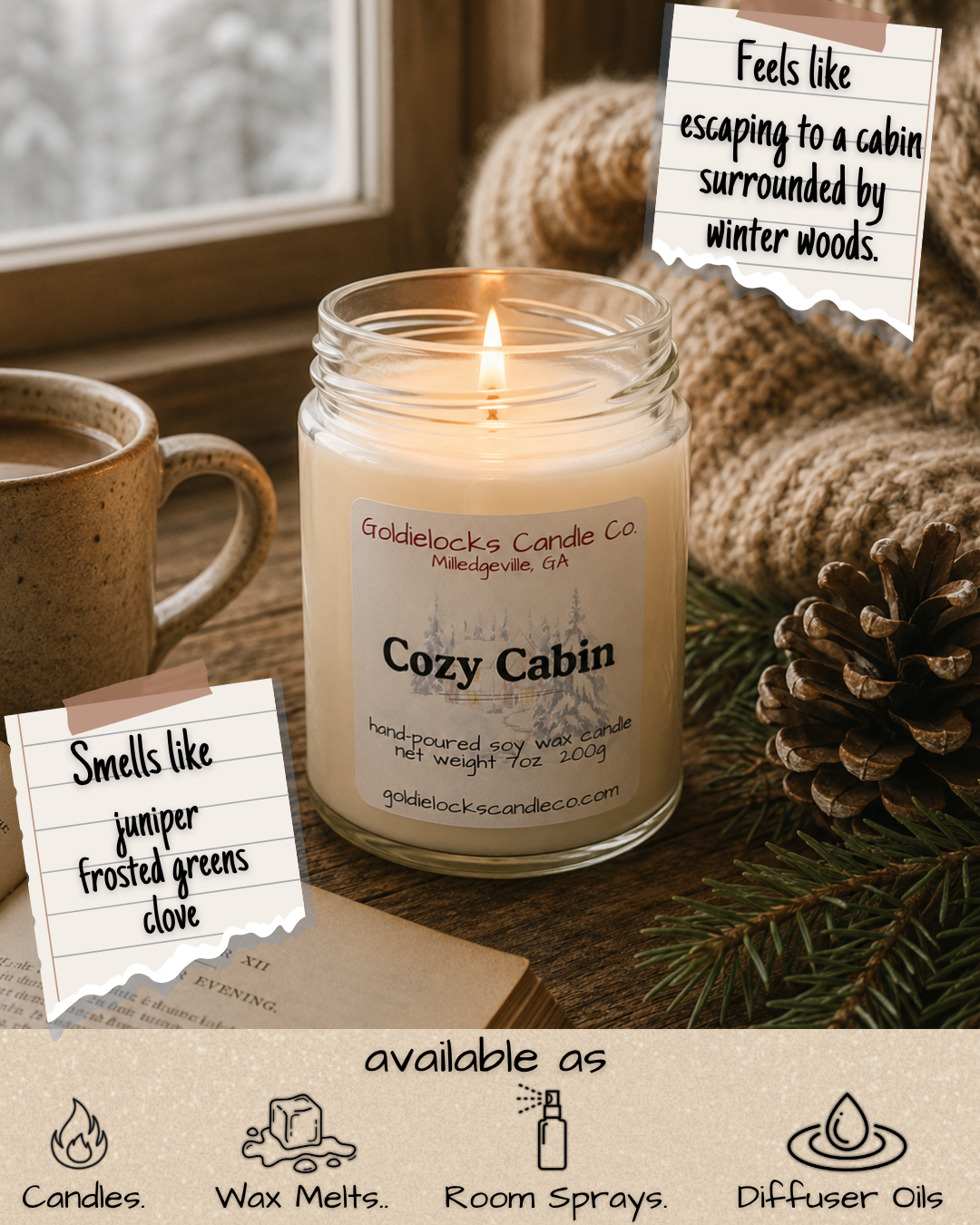 A lit candle labeled Cozy Cabin from Goldielocks Candle Co. on a wooden table near a mug of hot beverage, pine cones, and evergreen branches, with notes describing its scent of juniper, frosted greens, and clove, and a note stating it feels like escaping to a cabin in winter woods.