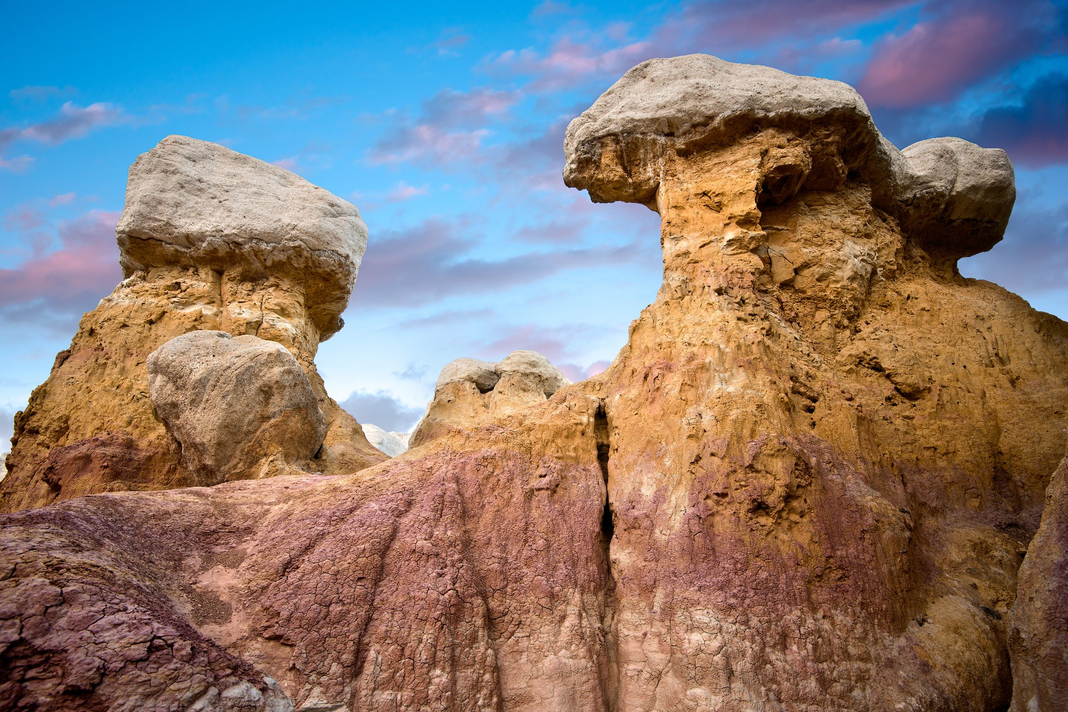 Large rock formations with a clear sky and pink and purple clouds in the background.