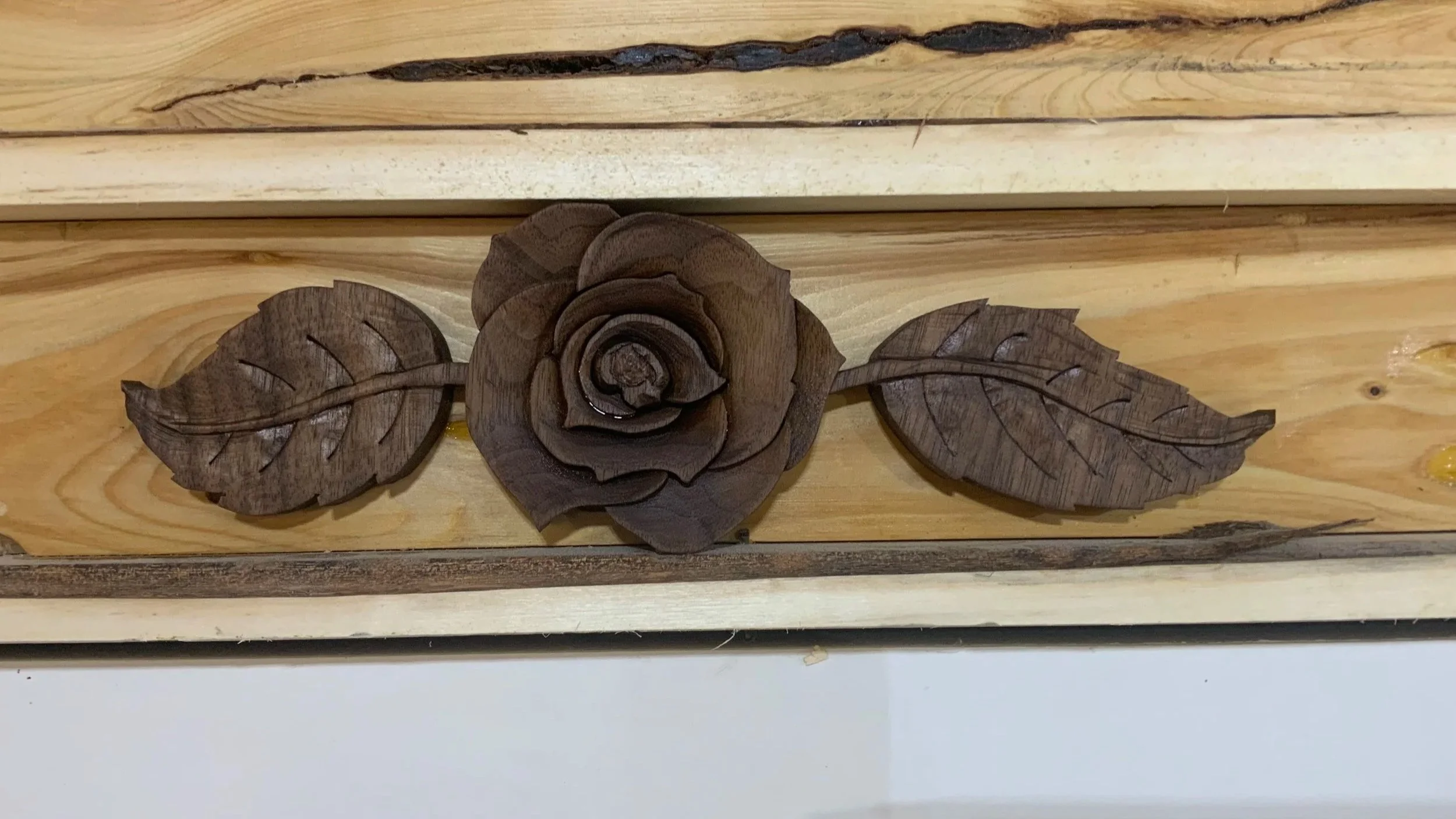 Wooden wall decoration featuring intricately carved rose and leaf design.