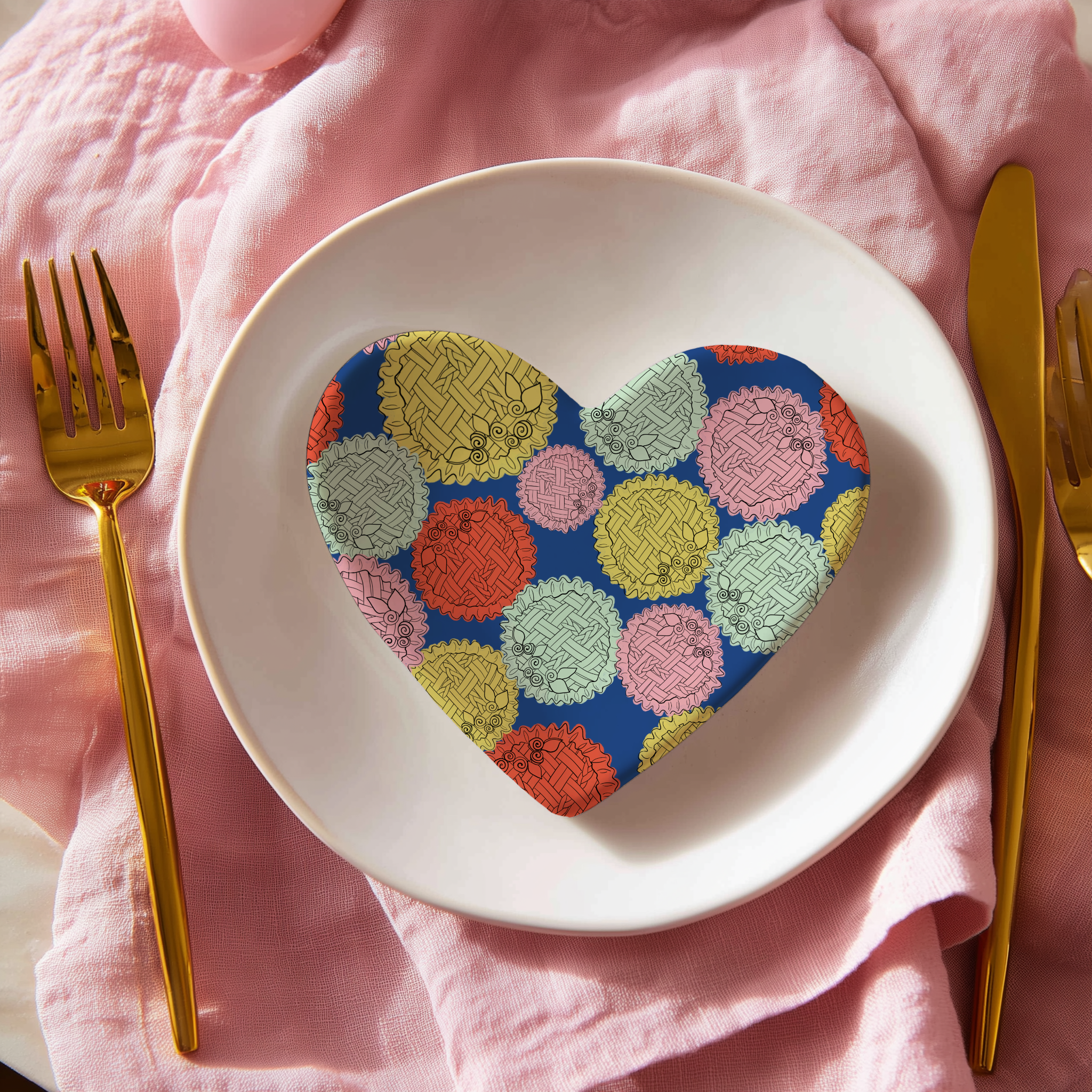 A white plate with colorful circular patterned coasters on it, placed on a pink cloth with a gold fork and knife beside it.