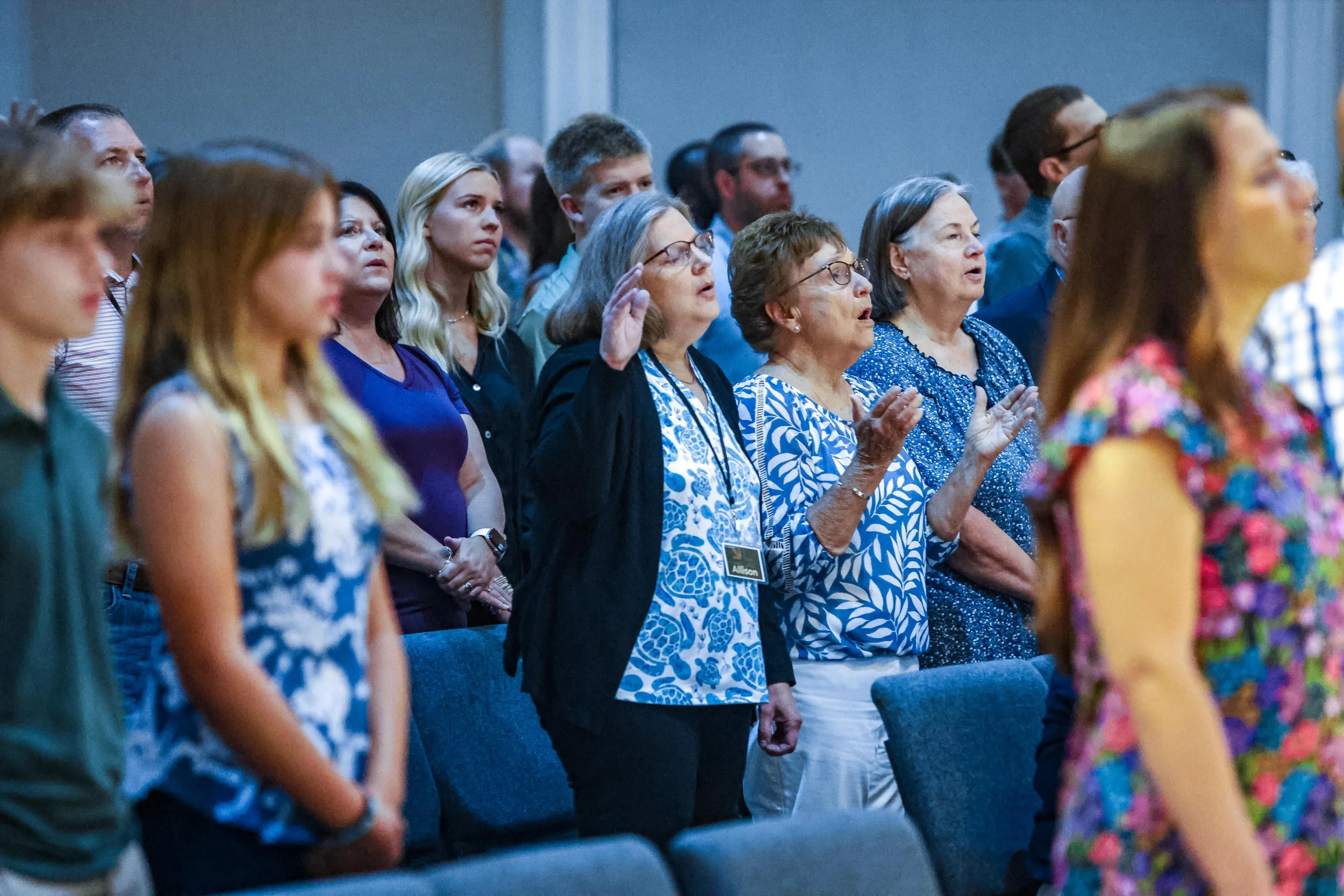 A diverse group of people standing and praying in a church or conference setting.